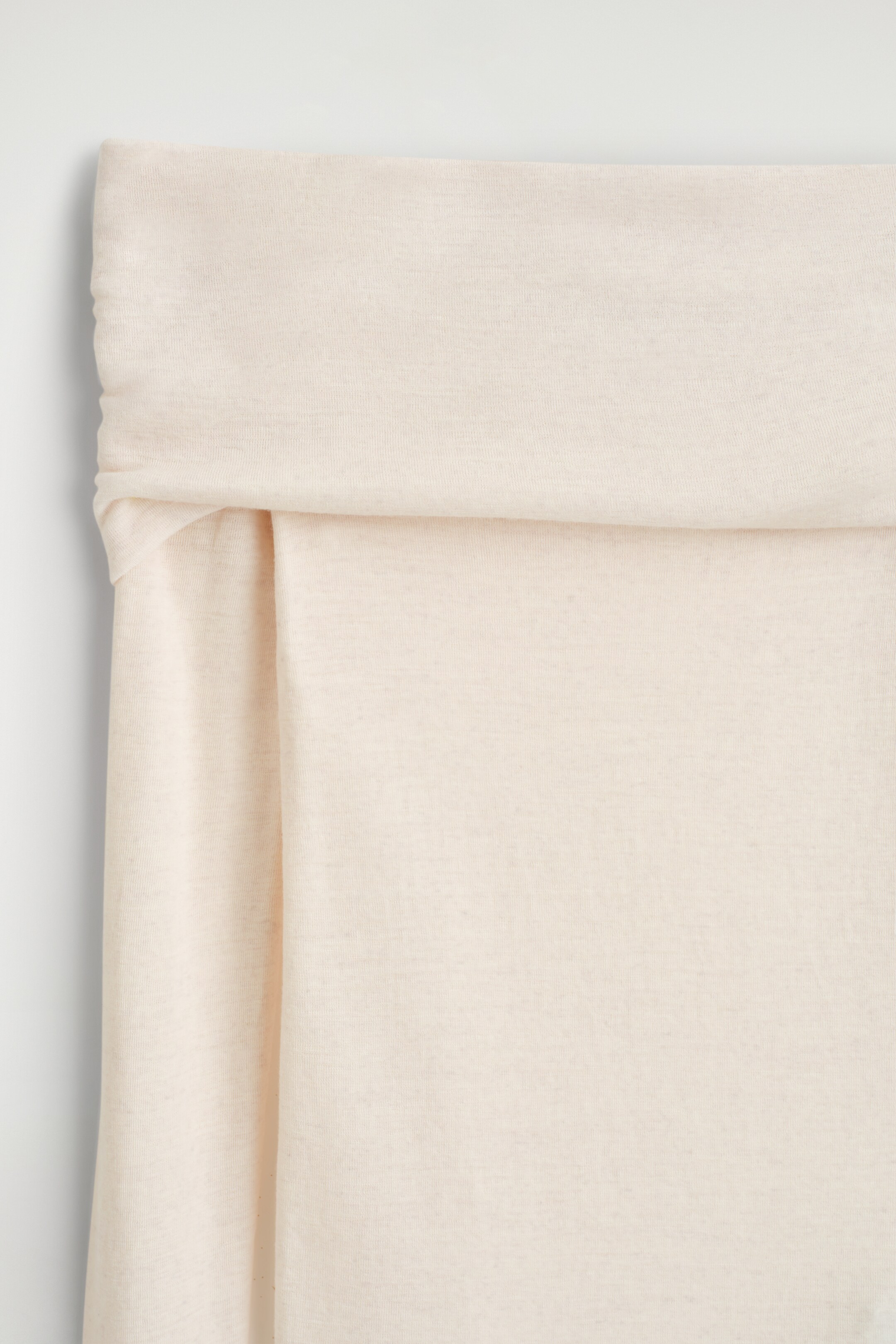 Agrandir l'image: Un haut beige clair à épaules dénudées est présenté, avec un large col bardot plié. Le tissu en laine mérinos à fine maille présente des drapés souples et une texture lisse.