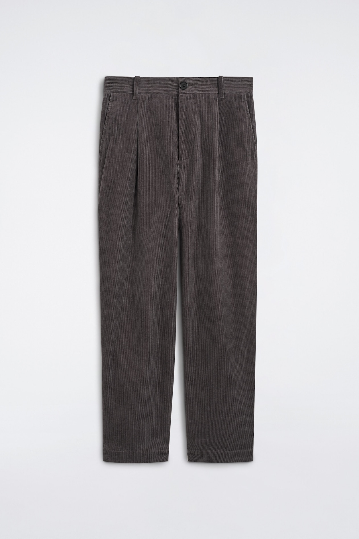 The corduroy relaxed-fit tapered pants are shown from the front, featuring dark gray fine-wale corduroy fabric with a button-closure waistband and belt loops. The design features single front pleats, side slit pockets, and legs that taper slightly toward the hem.