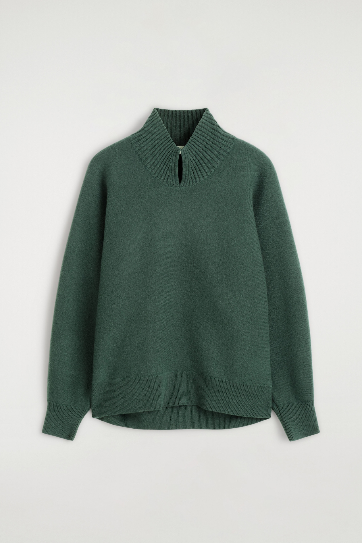 Un chandail en tricot vert foncé est présenté de face, mettant en valeur un col cheminée haut côtelé avec une petite fente en goutte à l'avant. Le vêtement affiche de longues manches avec des poignets côtelés et un ourlet côtelé à la coupe décontractée.