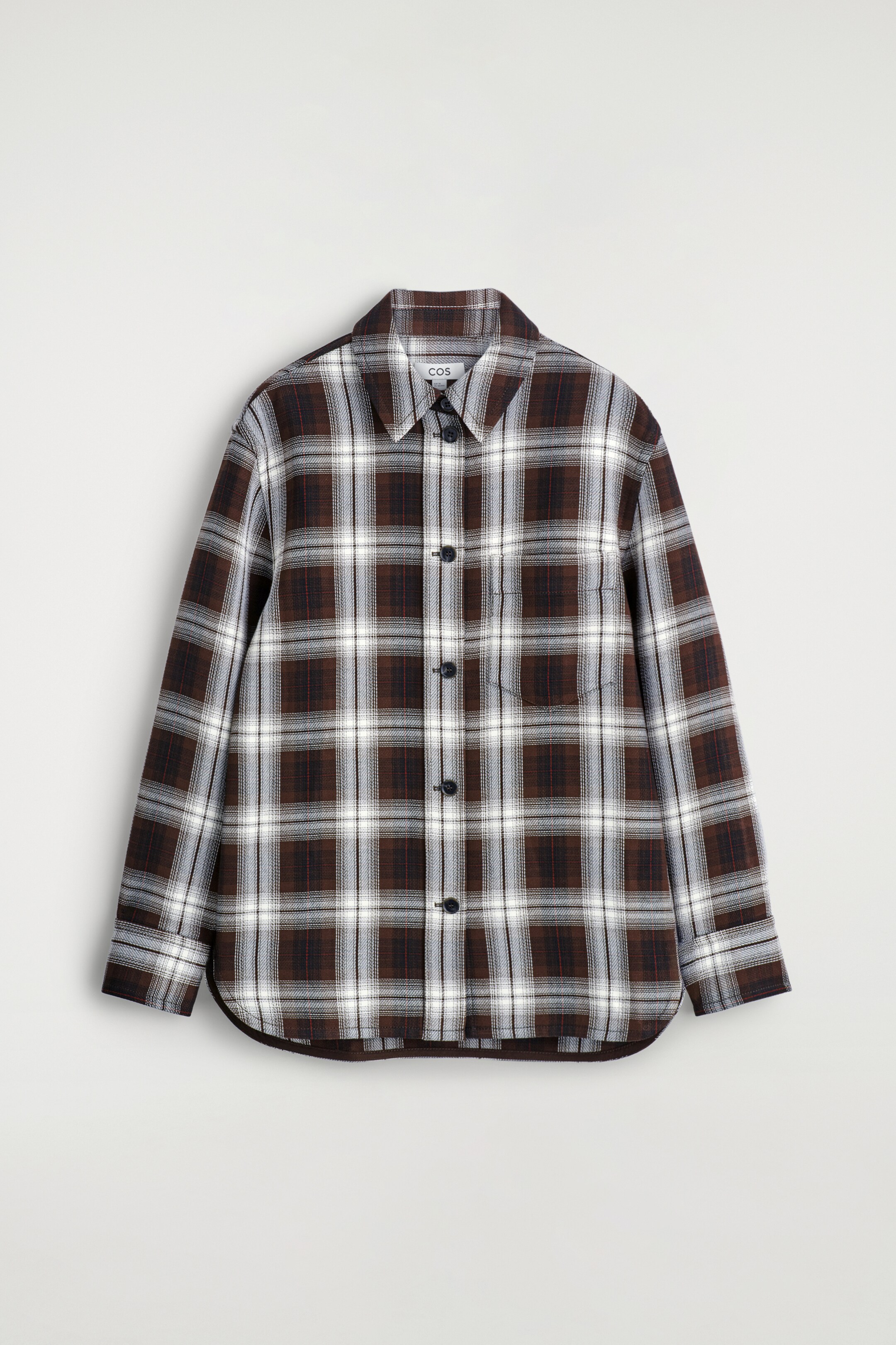 Visualizza immagine più grande: Una overshirt a vestibilità rilassata è presentata FRONTE, caratterizzata da un motivo a quadri marrone, bianco e grigio con sottili linee rosse. È progettata con un colletto a punta, una chiusura frontale con bottoni scuri, maniche lunghe con polsini con bottoni, una singola tasca applicata sul petto e un orlo curvo.