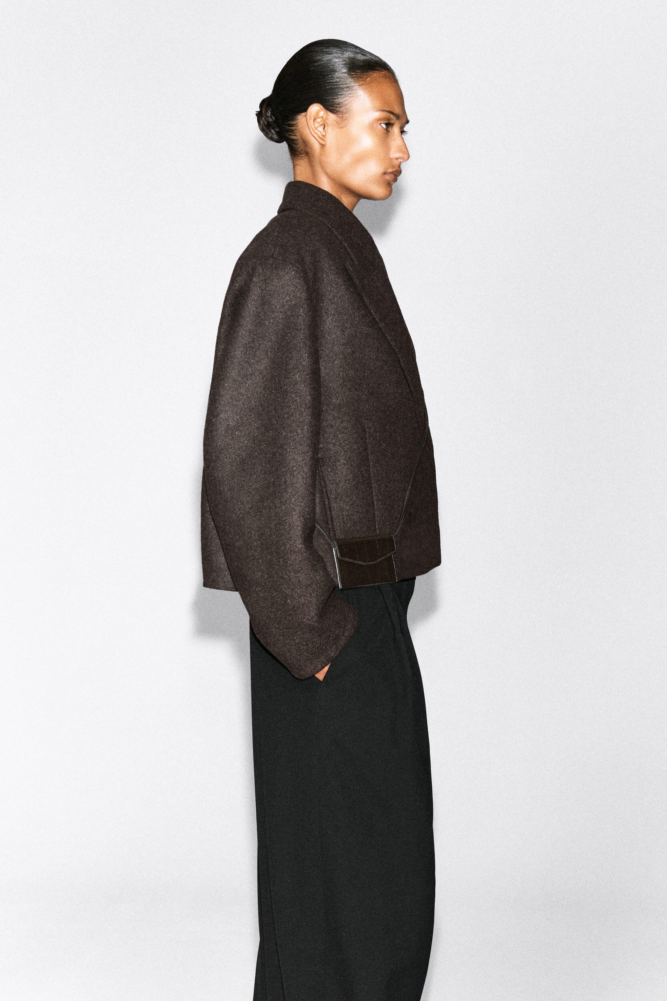 A dark brown eel-effect leather cardholder is being carried in the side pocket of the model’s dark brown wool jacket. The rectangular cardholder features a textured finish and a pointed envelope flap. A dark brown eel-effect leather cardholder is being carried in the side pocket of the model’s dark brown wool jacket. The rectangular cardholder features a textured finish and a pointed envelope flap.