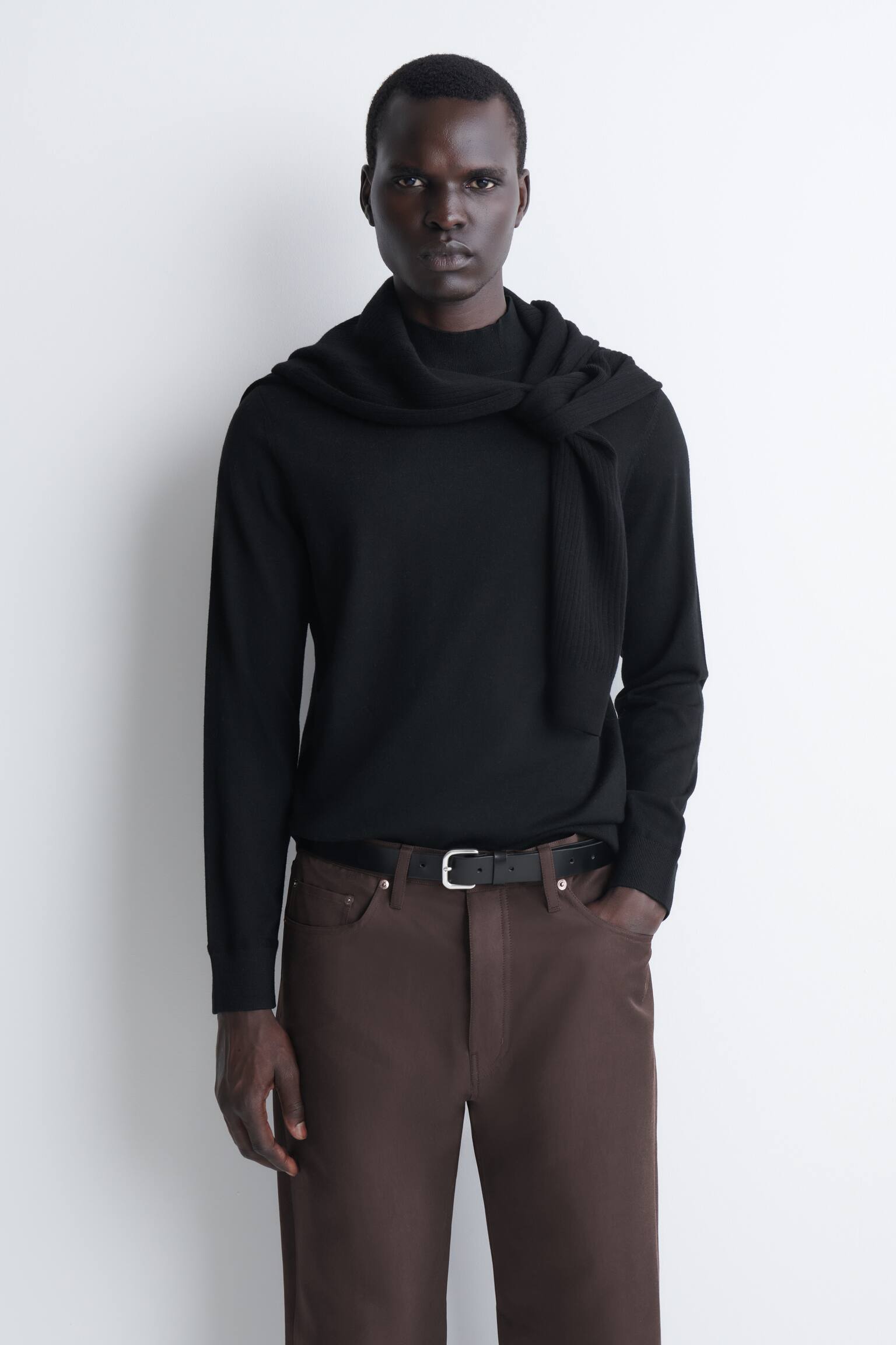 Um camisola preta slim em lÃ£ merino com gola subida Ã© apresentada de frente, com gola subida canelada, mangas compridas com punhos canelados e uma bainha canelada a condizer. A camisola apresenta uma textura lisa, de malha fina, e uma silhueta estruturada e clÃ¡ssica. - 1