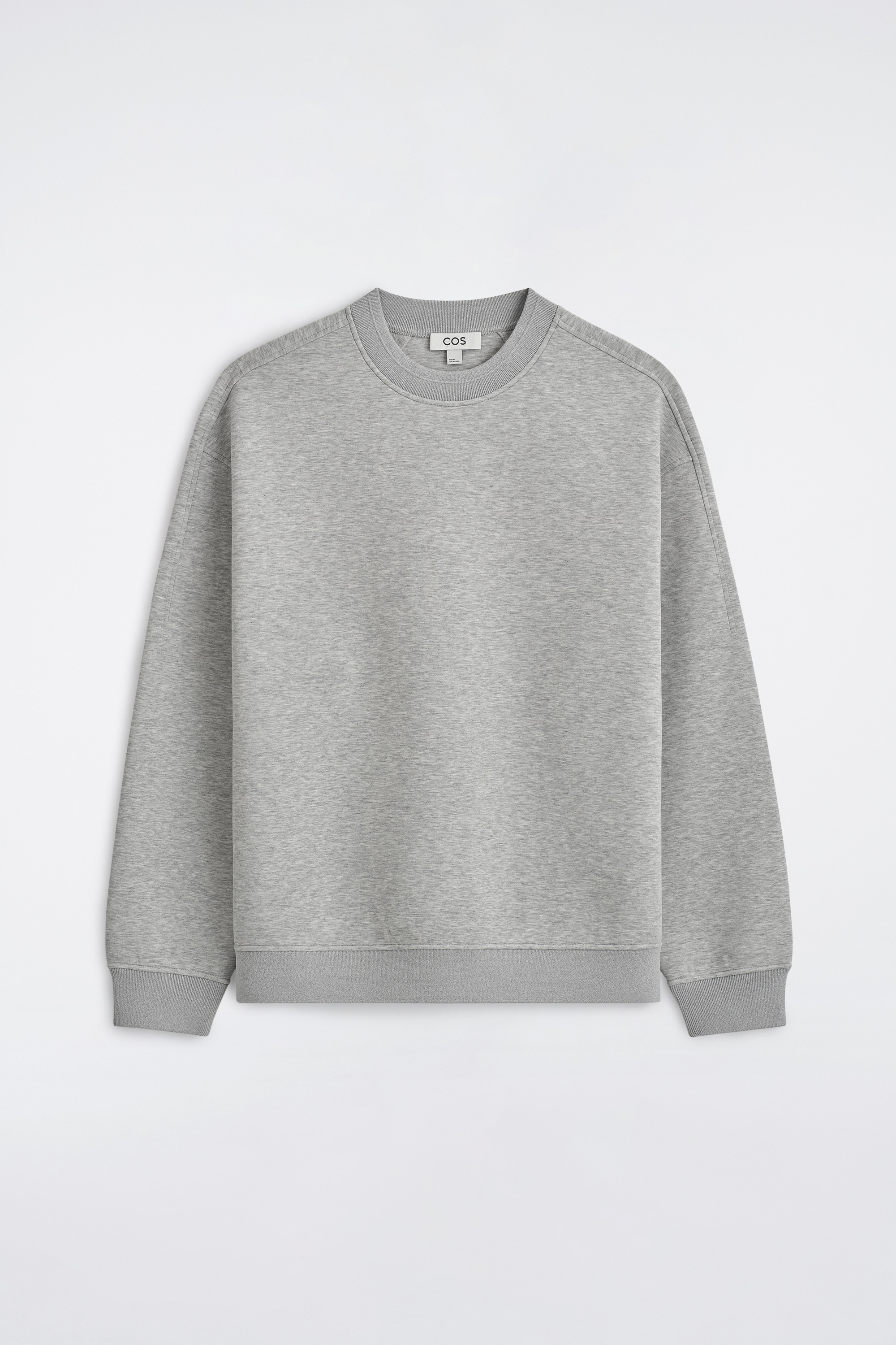Le sweat-shirt scuba coupe dÃ©contractÃ©e en gris clair prÃ©sente, vu de face, une coupe ample avec Ã©paules tombantes, poignets cÃ´telÃ©s et ourlet cÃ´telÃ©. Un col de chemise Ã  rayures dÃ©passe subtilement sous lâencolure ronde, illustrant un style superposÃ©.