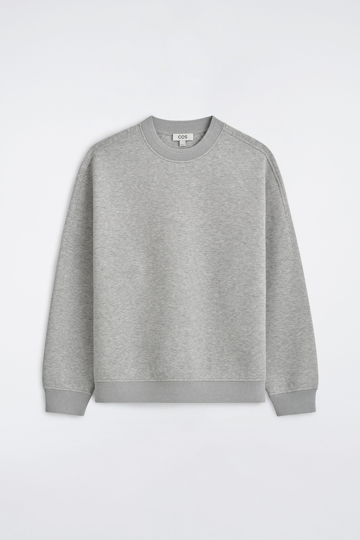 The Relaxed Scuba Sweatshirt is shown in a front view, featuring a light grey mélange fabric and a relaxed fit with dropped shoulders. It includes a classic ribbed crew neck, ribbed cuffs, and a matching ribbed hem.