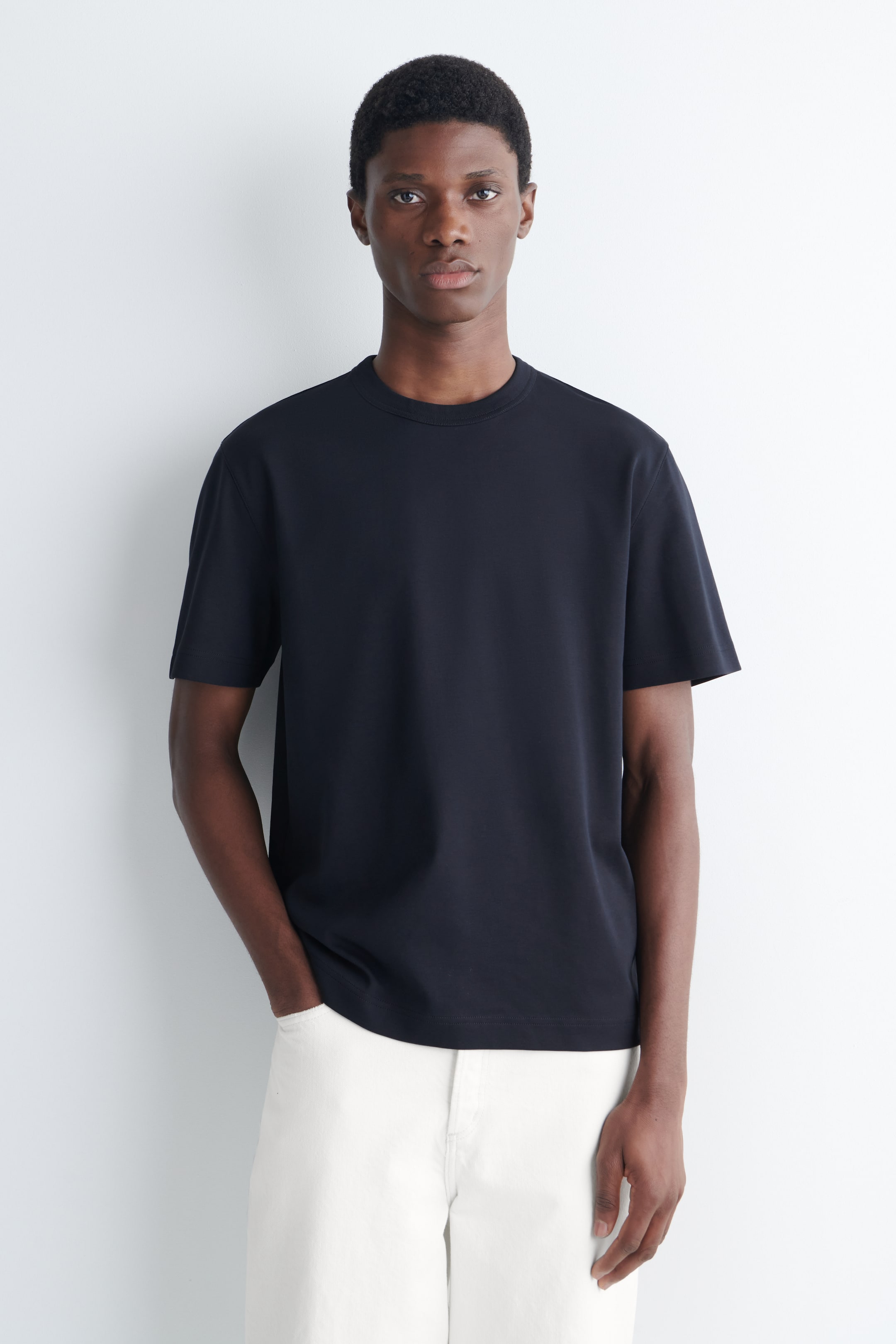 Grotere afbeelding bekijken: Een donkerblauw T-shirt met een ronde hals en korte mouwen. Het heeft een ontspannen pasvorm met een gladde stof en een rechte zoom, naar voren gericht.