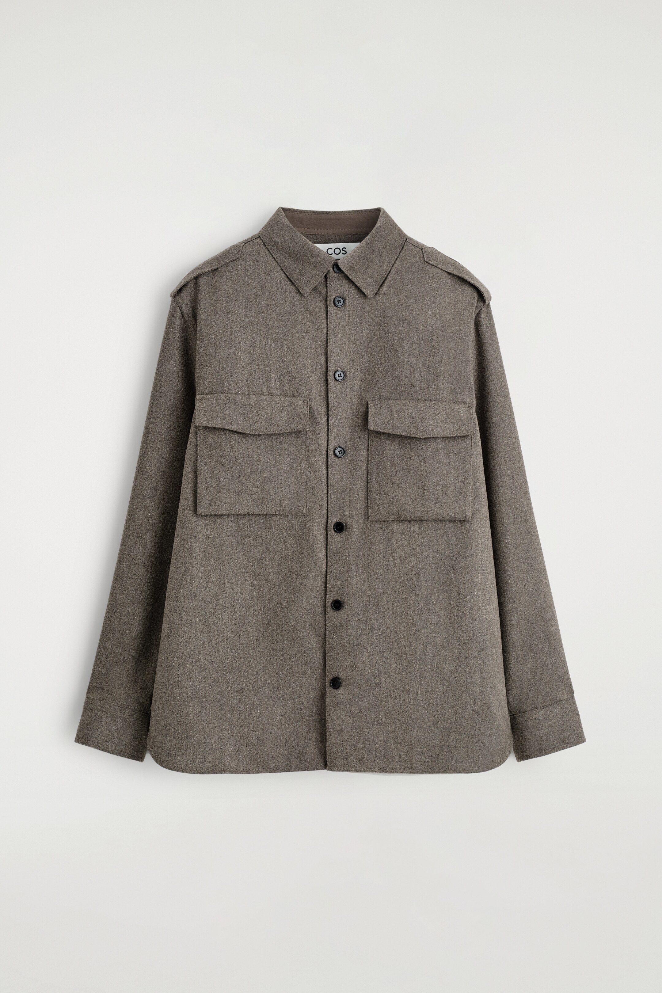 Agrandir l'image: Une chemise utilitaire gris-brun chiné est présentée de face, offrant une coupe décontractée. Elle est confectionnée dans un tissu texturé, semblable à de la laine, et présente un col classique, une fermeture à boutons noirs, deux grandes poches à rabat sur la poitrine et des épaulettes sur les épaules.