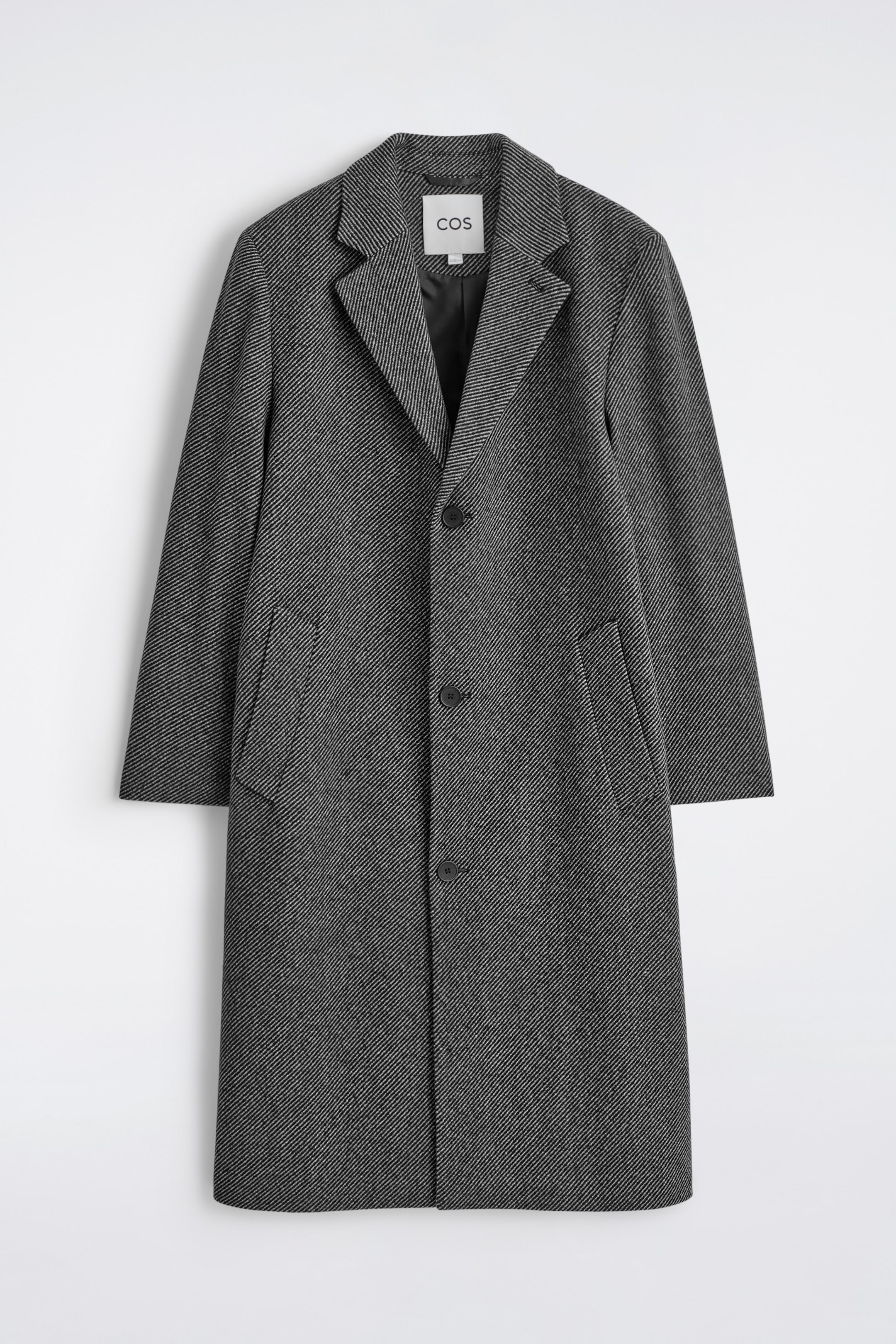 Agrandir l'image: Un long manteau gris foncé est montré de face, présentant une coupe décontractée et un motif texturé diagonal subtil. Il est doté de revers crantés, d'une fermeture à trois boutons et de deux poches passepoilées à l'avant.