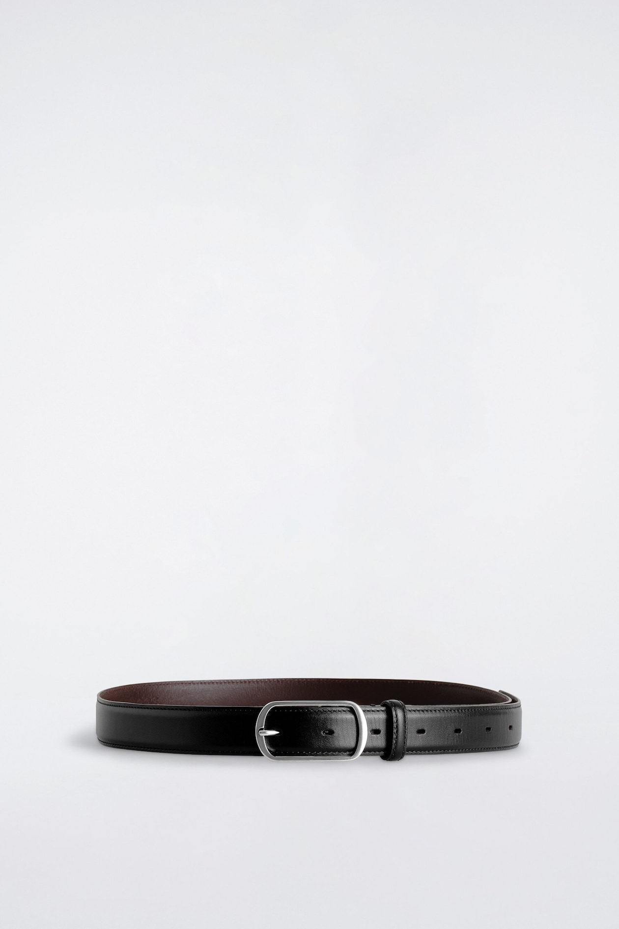 The curved-buckle leather belt is resting in a rounded loop, facing forward, showcasing its smooth black leather exterior with tonal edge stitching and a contrasting brown inner lining. It features a polished, silver-tone curved rectangular buckle, along with a matching leather keeper loop and pre-punched adjustment holes.