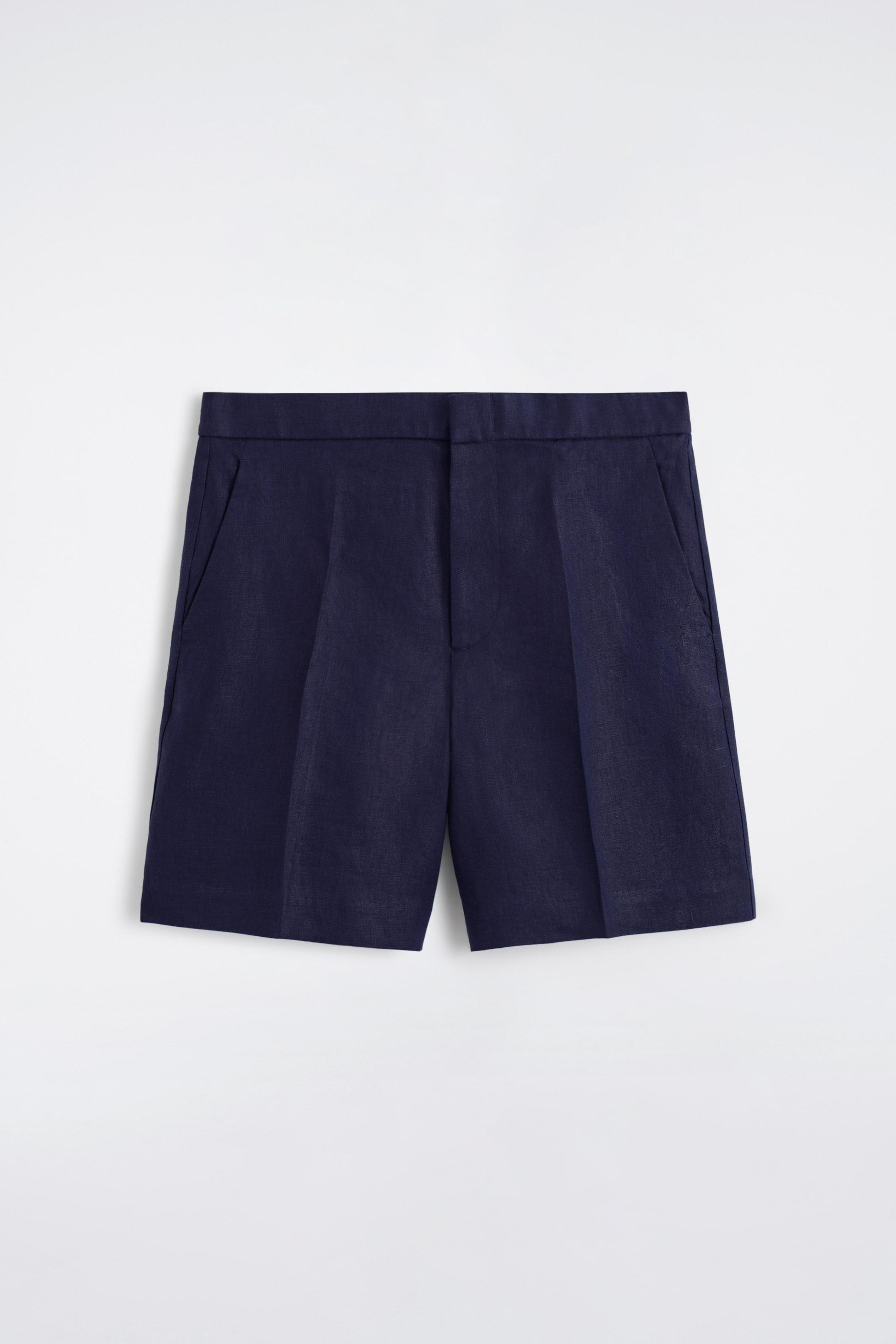 Visualizza immagine più grande: I pantaloncini in lino blu navy presentano una cintura piatta, una chiusura con zip e tasche laterali a fessura sul davanti. Le gambe dritte mostrano pieghe prominenti.