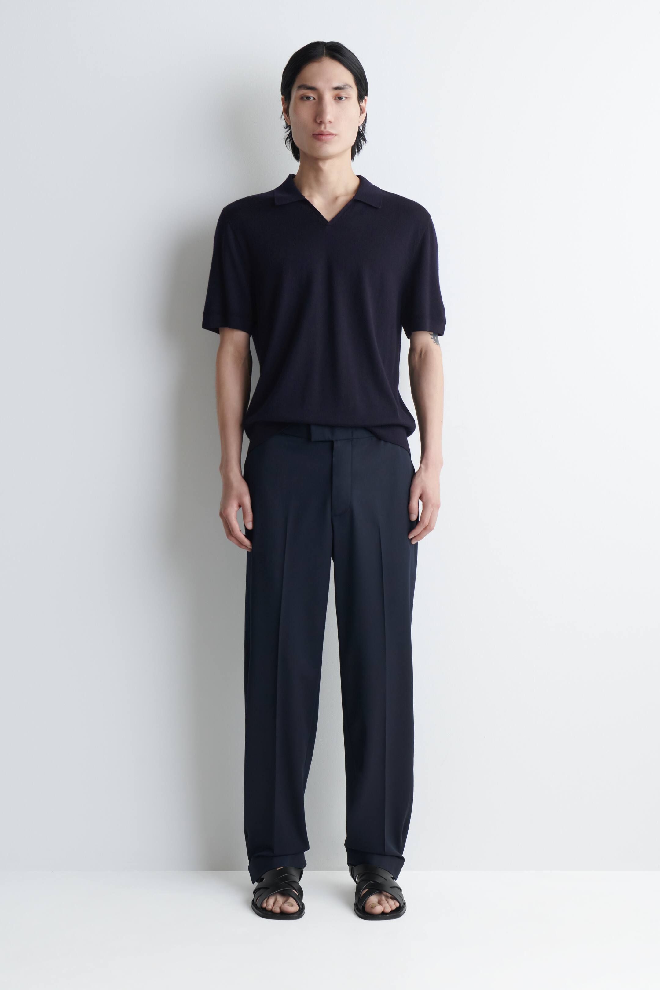 View larger image: Dark navy straight-leg trousers with visible pressed creases are being worn by the model.