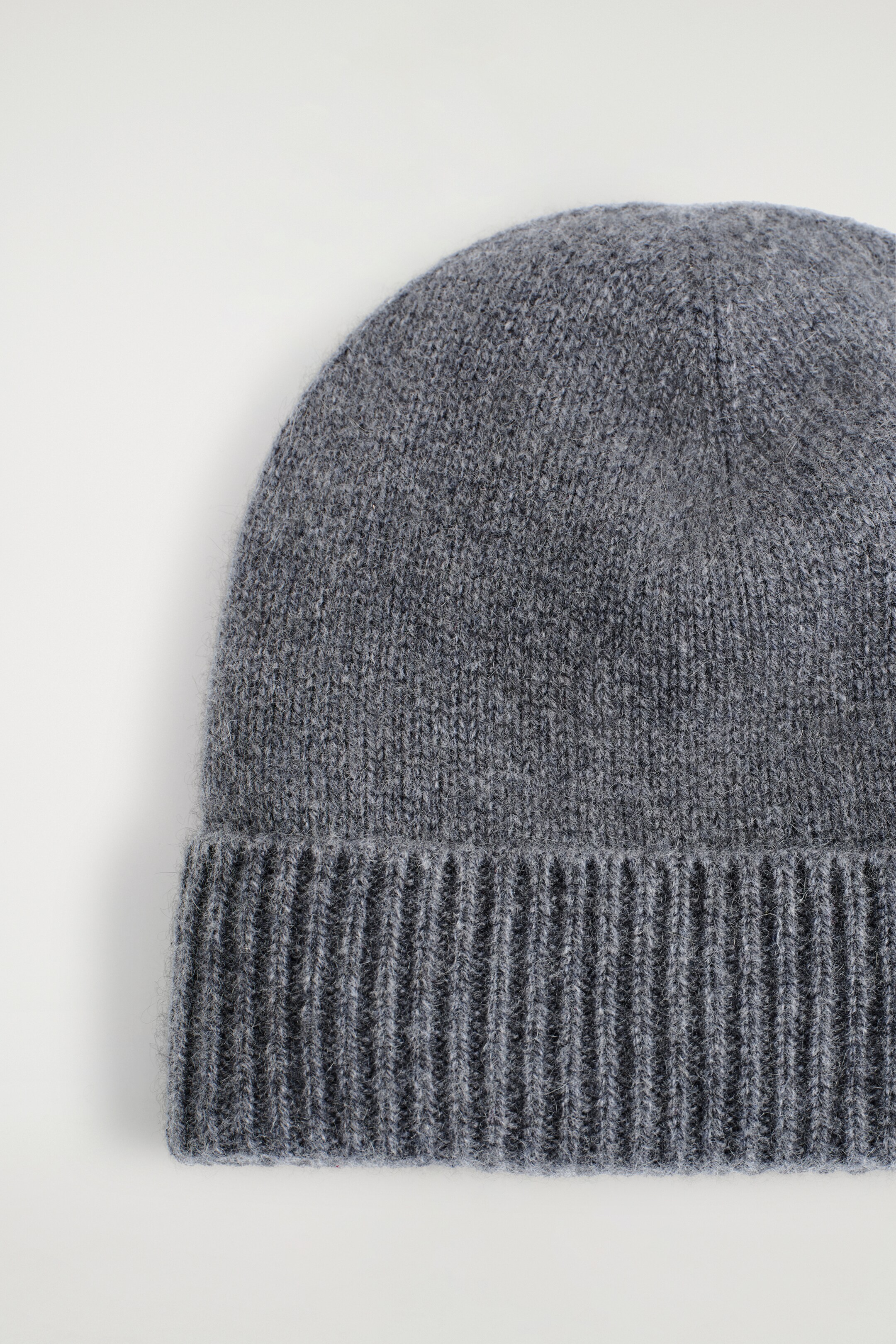 Ver imagem maior: Um gorro cinzento é mostrado de frente. Apresenta uma textura tricotada e uma aba larga, canelada e dobrada.
