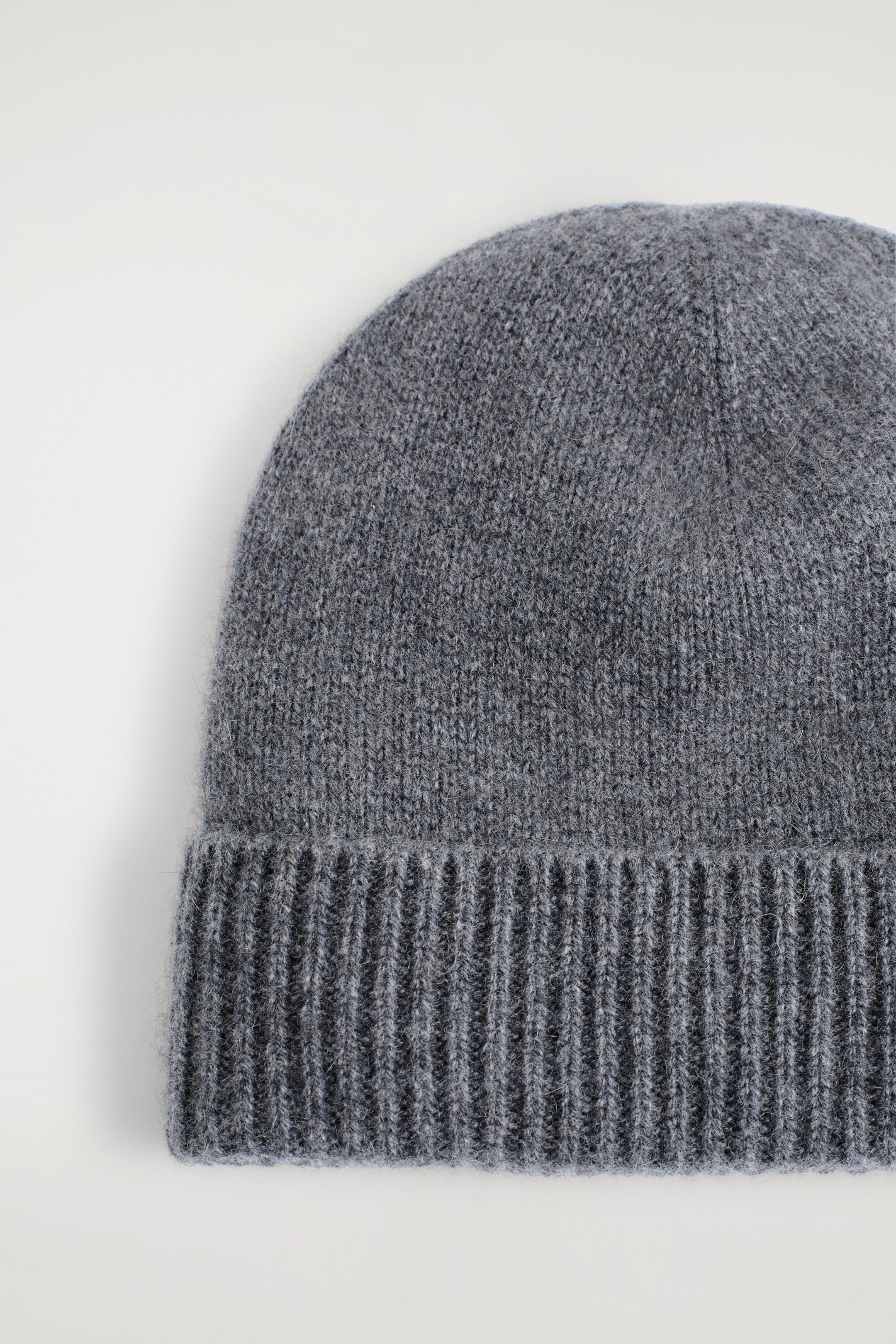 Agrandir l'image: Un bonnet gris est montré de face. Il présente une texture tricotée et un large bord replié et côtelé.