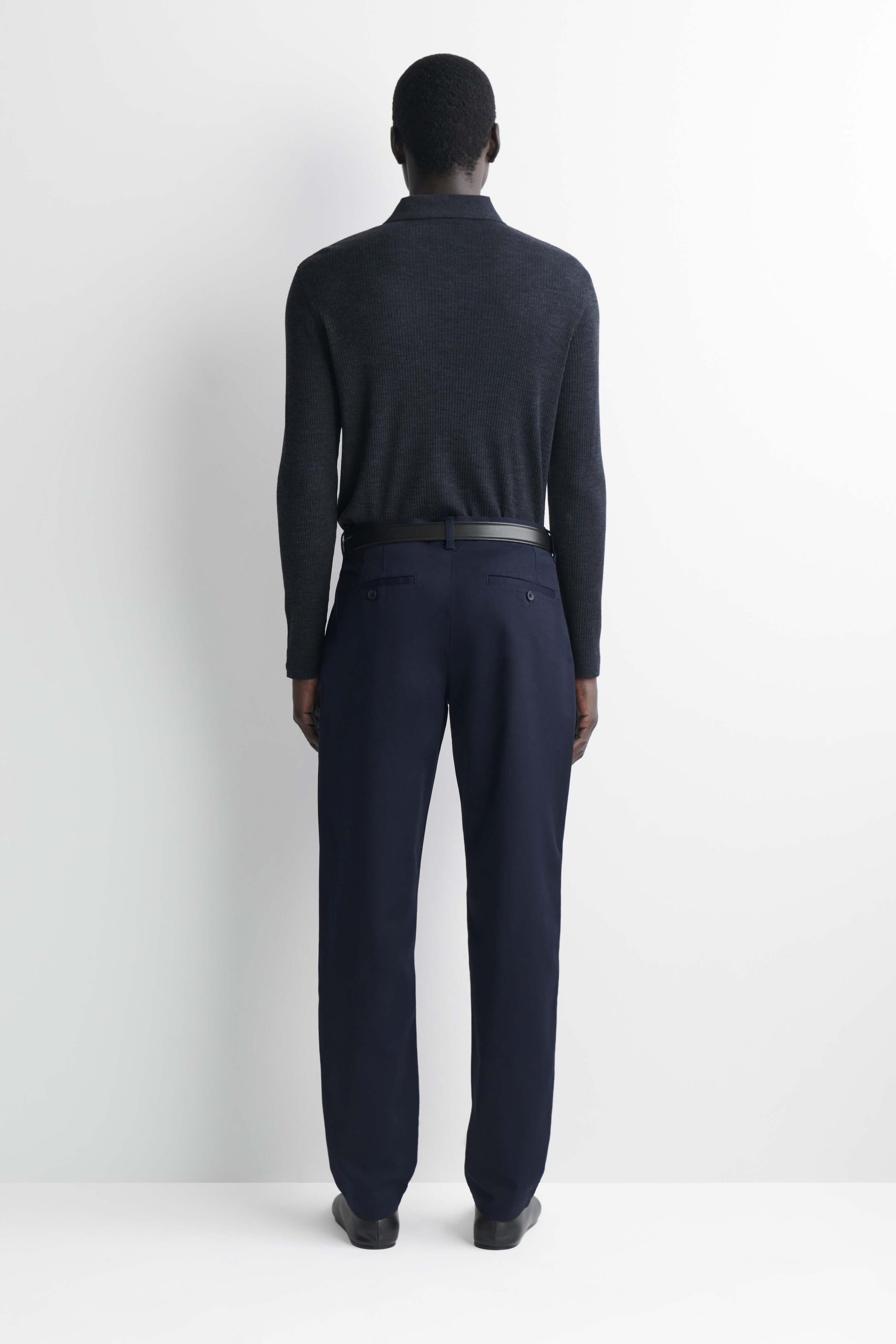 Questi chinos slim fit a gamba dritta in cotone sono mostrati dal retro, mettendo in evidenza il tessuto blu navy scuro, la silhouette a gamba dritta e la sartorialità pulita. Presentano passanti per cintura abbinati a una cintura in pelle nera e due tasche posteriori a filetto con bottone, con una maglia a maniche lunghe grigio scuro infilata in vita. Questi chinos slim fit a gamba dritta in cotone sono mostrati dal retro, mettendo in evidenza il tessuto blu navy scuro, la silhouette a gamba dritta e la sartorialità pulita. Presentano passanti per cintura abbinati a una cintura in pelle nera e due tasche posteriori a filetto con bottone, con una maglia a maniche lunghe grigio scuro infilata in vita.