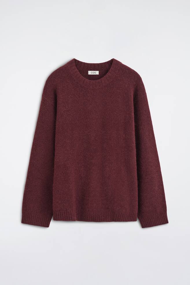 En oversized genser med rund hals i alpakka-blanding i en dyp burgunderfarge presenterer en avslappet, lÃ¸s silhuett sett forfra. Plagget har en lodden, strukturert strikk med ribbestrikket rund hals, senkede skuldre, ribbestrikkede mansjetter og ribbestrikket kant. - 1