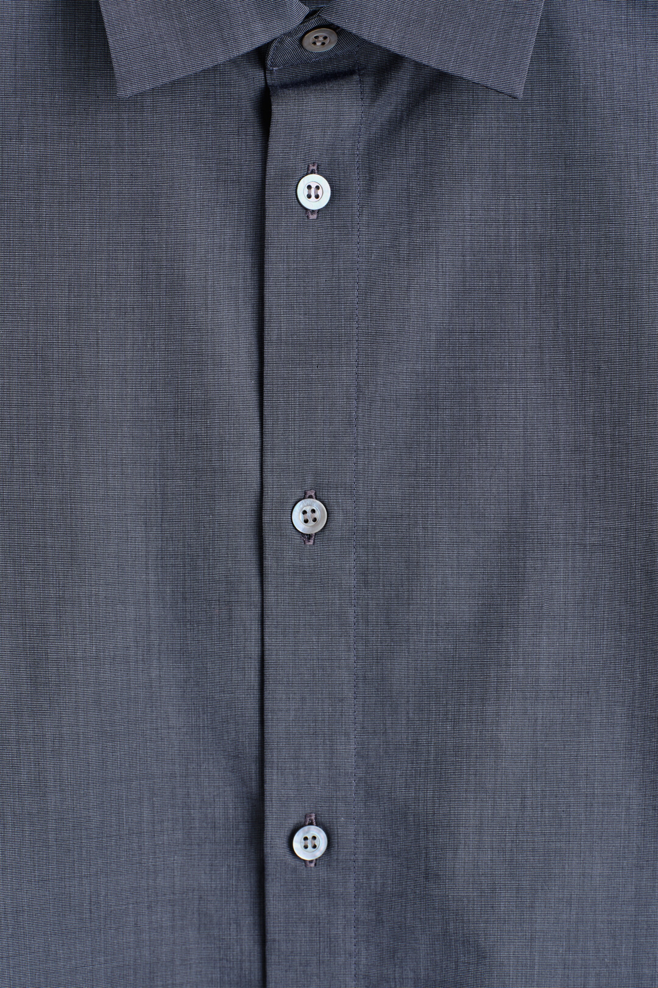 Agrandir l'image: Une chemise gris foncé présente son devant, mettant en valeur un tissage finement texturé et subtil. Sa patte de boutonnage centrale présente trois boutons blancs visibles à quatre trous, et un col pointu apparaît en haut.