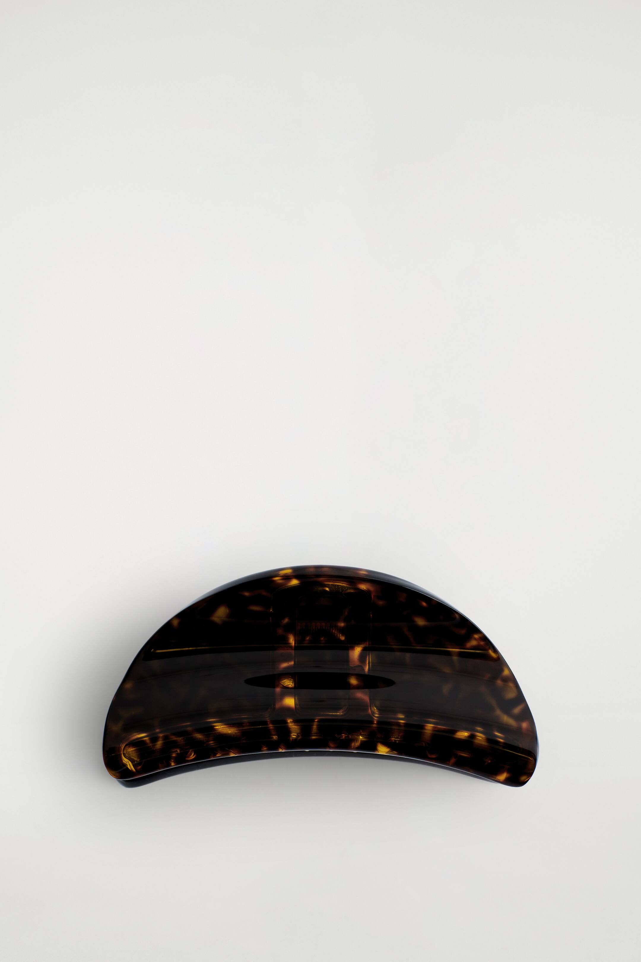 הצגת תמונה גדולה יותר: קליפס לשיער מציג דוגמת שריון צב בגוונים של חום כהה וענבר. הוא כולל חלק עליון מעוגל וקמור עם שקע אובלי מוארך וכהה במרכז.