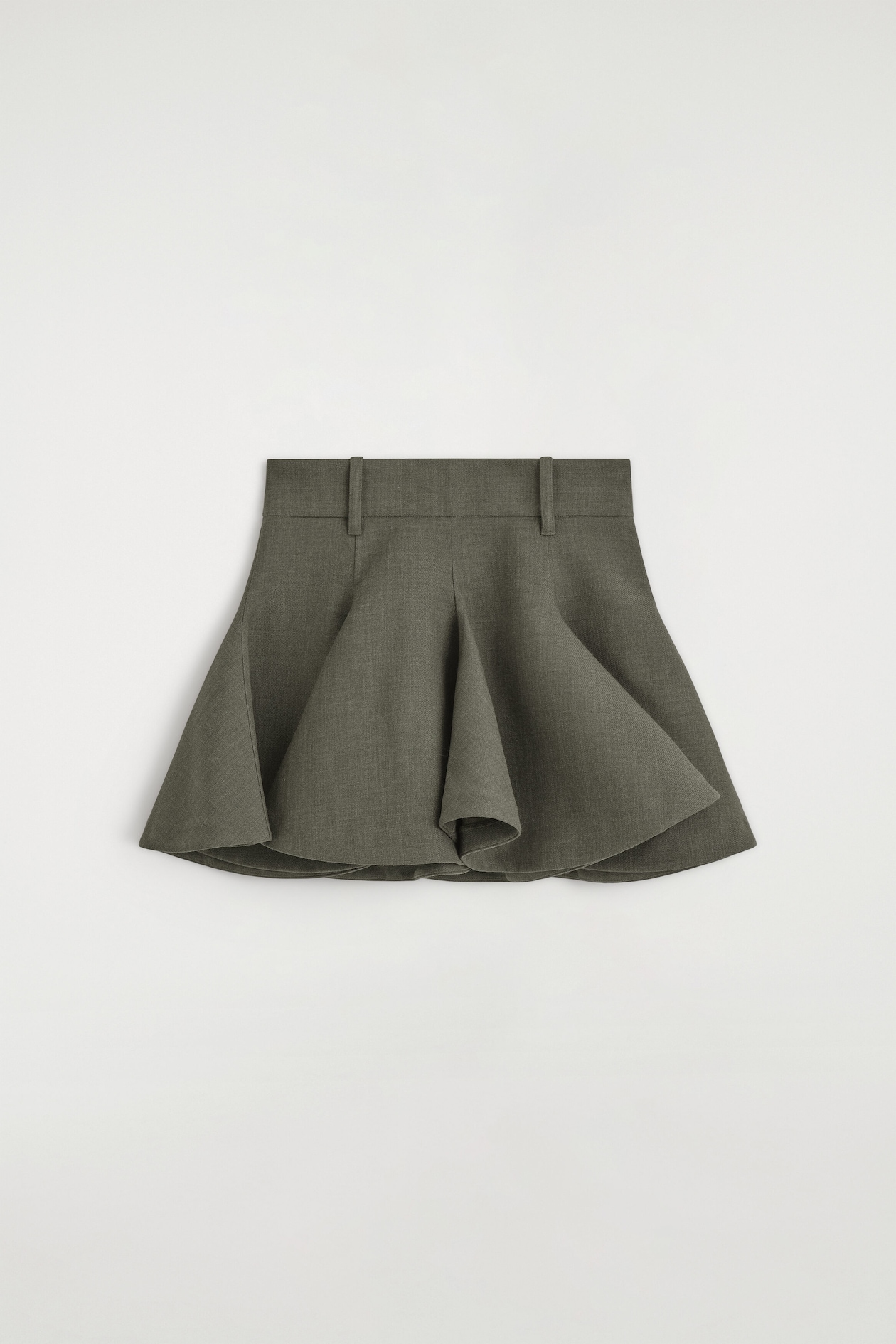 The sculptural tailored wool mini skirt is shown in a front-facing view, featuring a structured waistband with belt loops. The olive-gray fabric drapes into deep, voluminous folds, creating a highly flared, architectural silhouette.