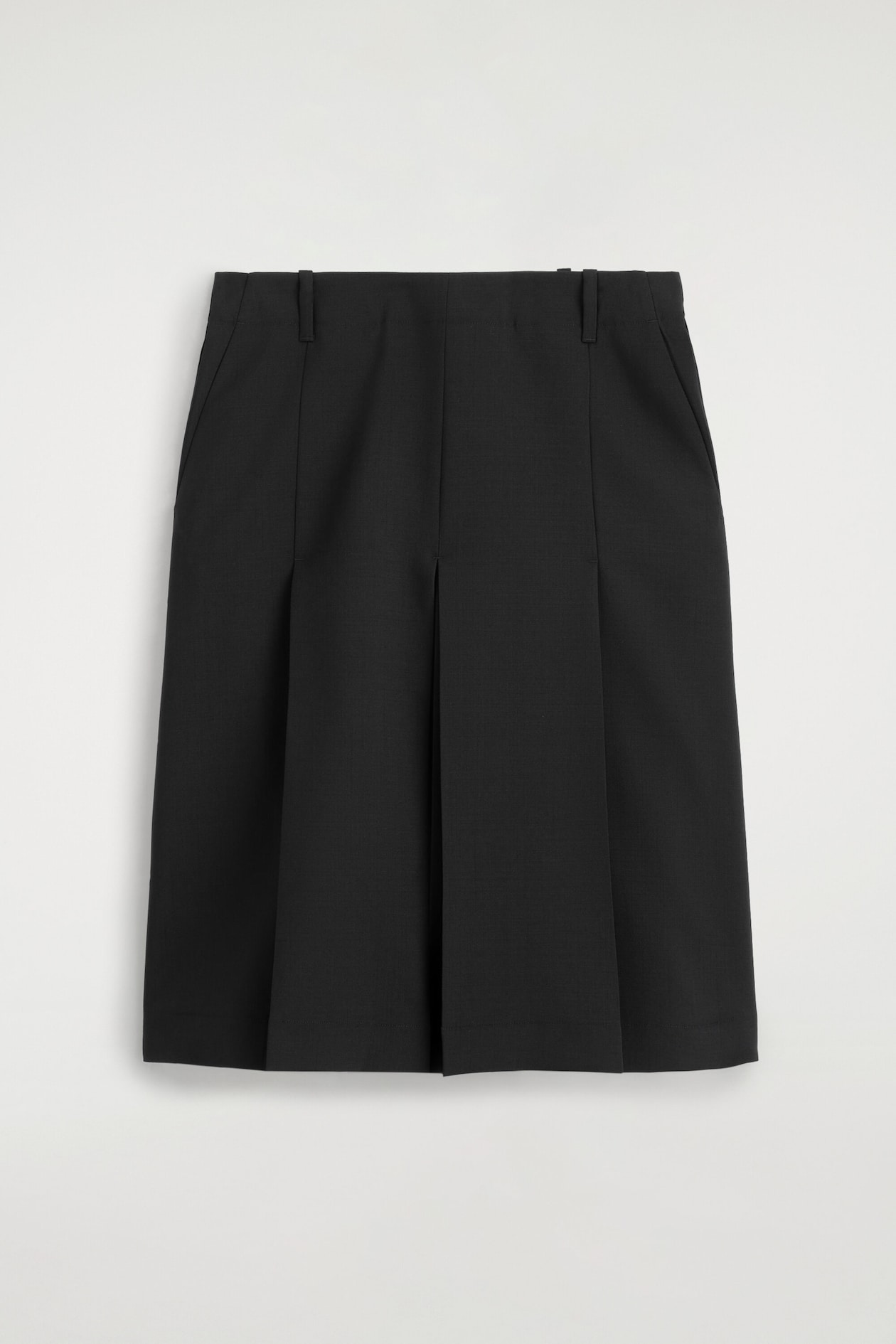 A box-pleat midi skirt is shown front-facing in black fabric. It features two box pleats at the center front, a flat waistband with belt loops, and side slit pockets.