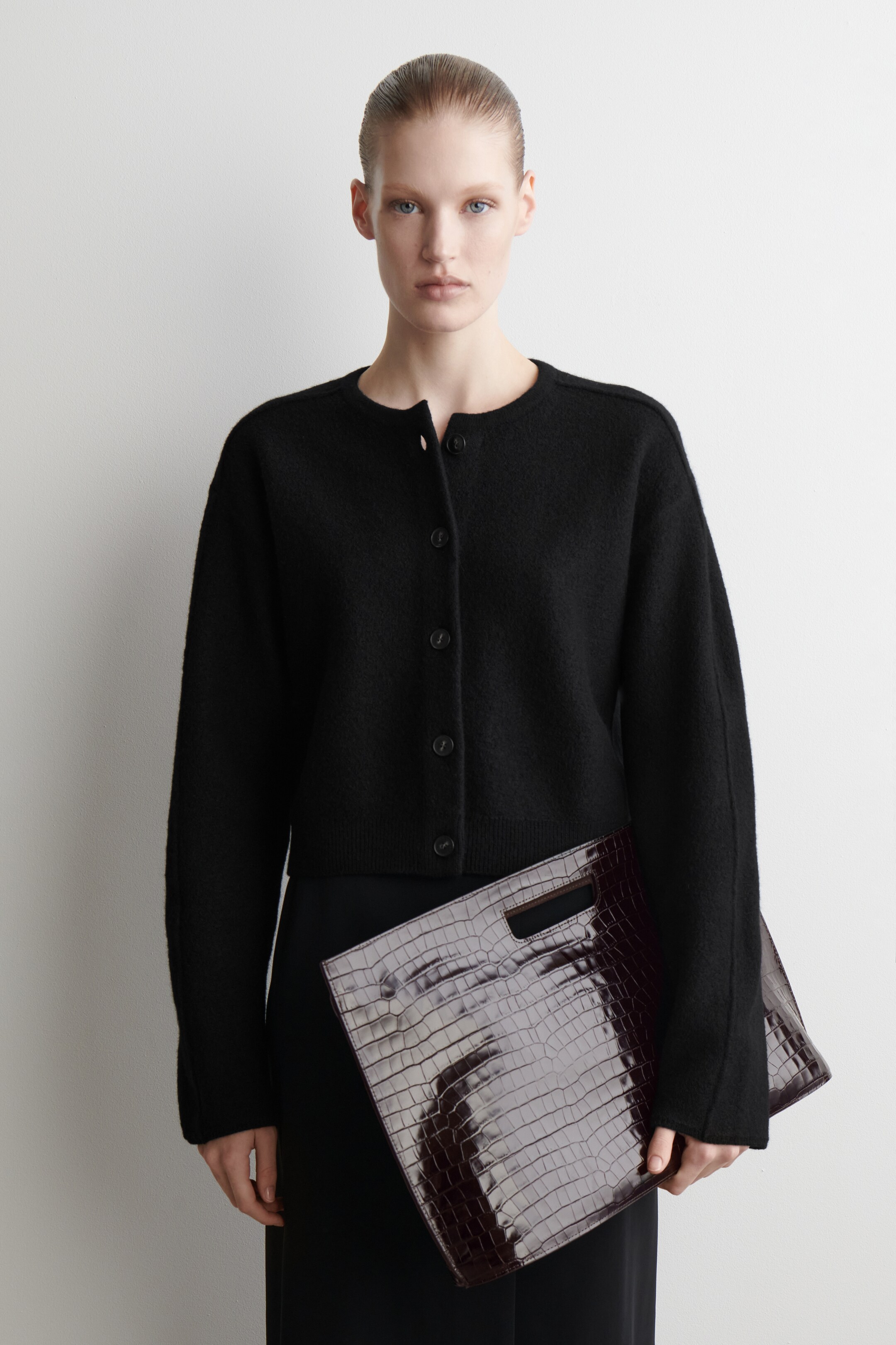 Agrandir l'image: Un cardigan en maille duveteuse noire est exposé de face, avec un col rond et une fermeture complète à boutons avec six boutons foncés. Il présente des manches longues avec des poignets côtelés et un ourlet côtelé, coupé à une longueur légèrement raccourcie.