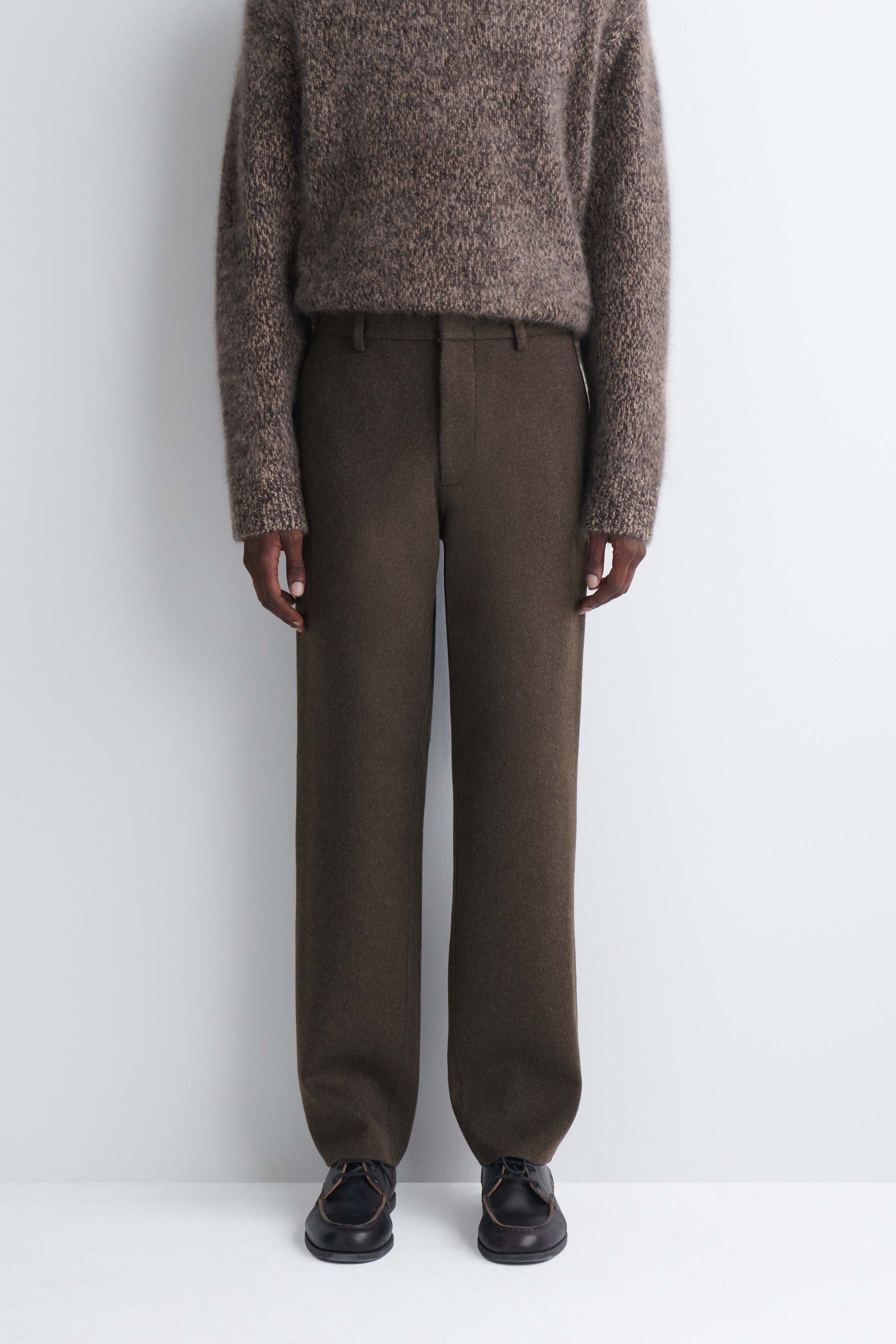 Double-faced wool-blend straight-leg pants in a dark olive-brown color are worn by the model. The pants feature a structured straight-leg silhouette with belt loops and are styled with a textured brown melange knit sweater and dark leather shoes. Double-faced wool-blend straight-leg pants in a dark olive-brown color are worn by the model. The pants feature a structured straight-leg silhouette with belt loops and are styled with a textured brown melange knit sweater and dark leather shoes.
