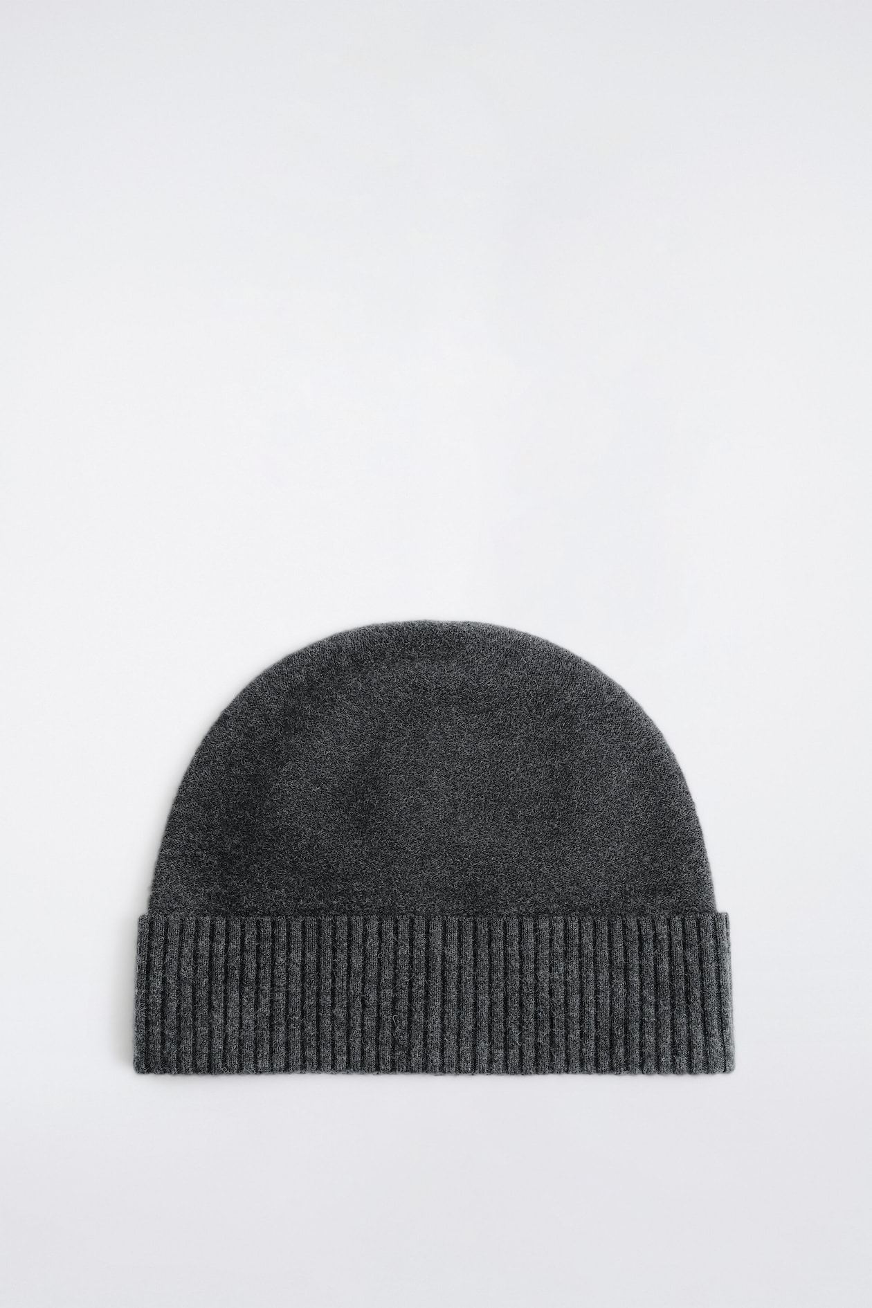 A dark grey knit toque is shown from the front, featuring a textured, dense wool body and a wide, ribbed fold-up brim.