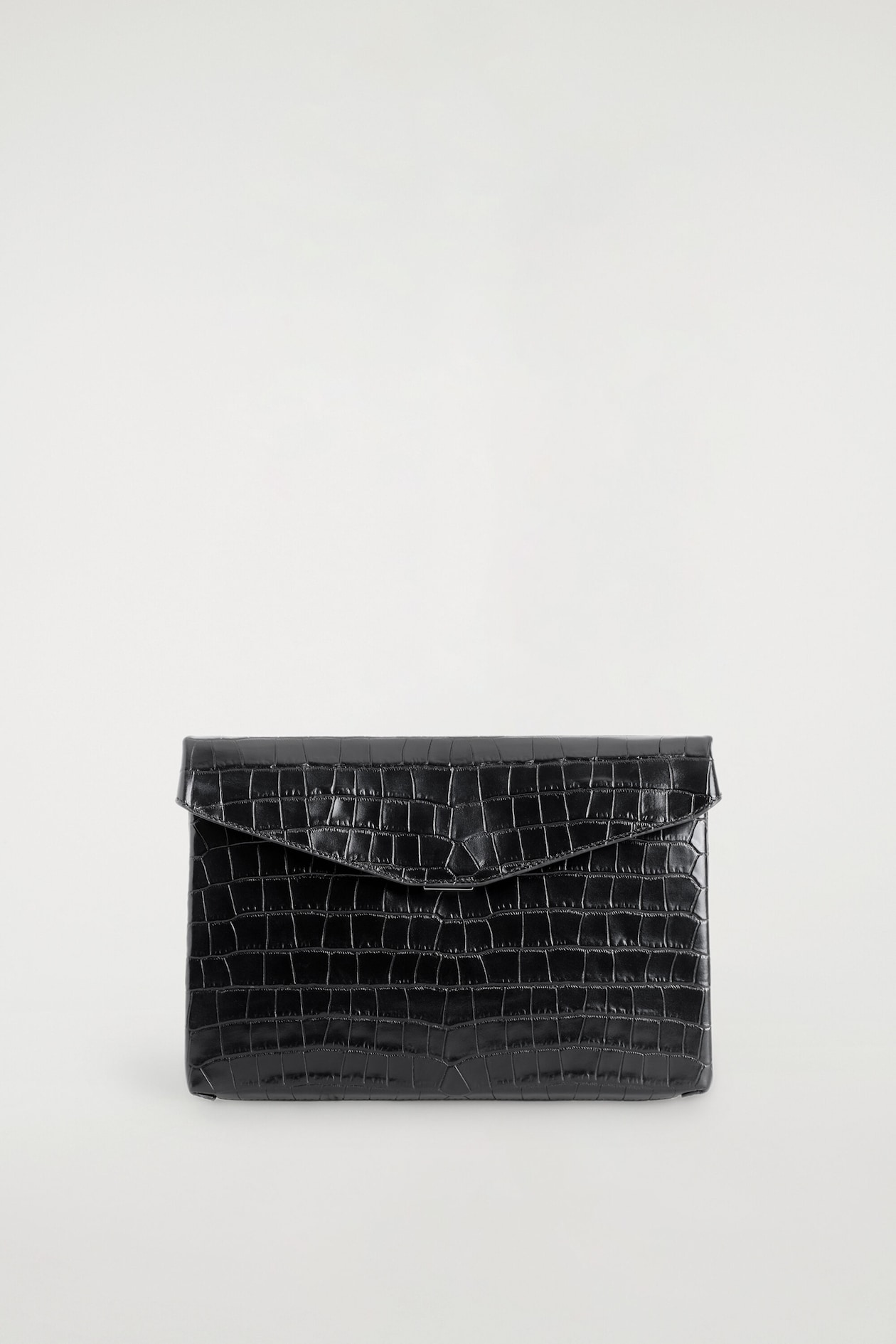 An envelope-clasp pouch in black croc-effect leather is shown from the front, highlighting its structured rectangular silhouette and glossy embossed texture. It features a pointed envelope-style flap that folds over the front and secures with a discreet metal clasp.
