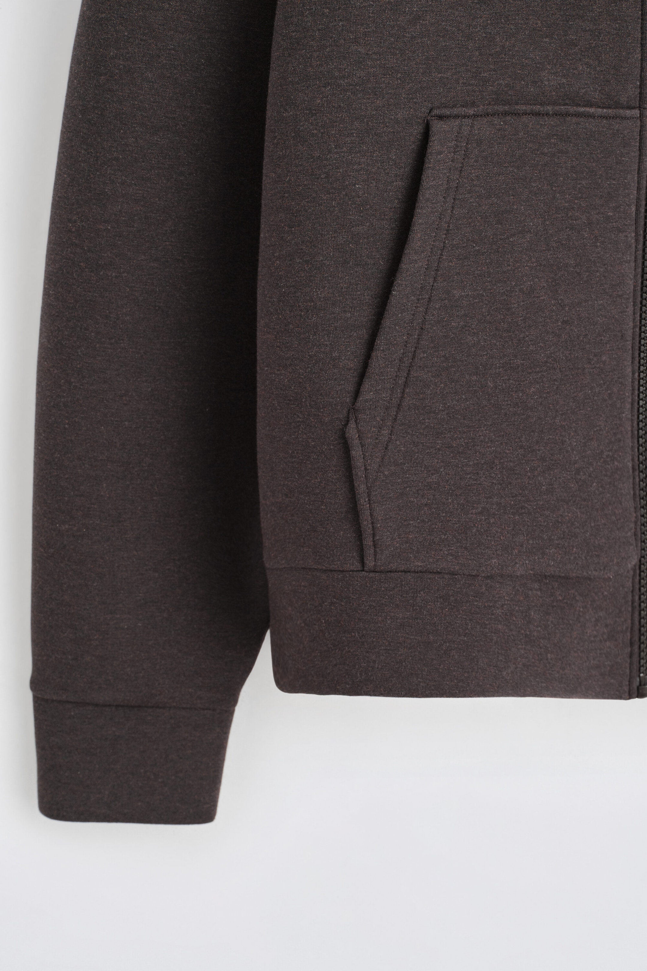 The oversized scuba jersey zip-up hoodie is shown in a close-up front view, highlighting its dark brown heathered fabric. It features a front patch pocket with a slanted opening, a wide self-fabric sleeve cuff, and a structured hem band alongside the zipper edge. The oversized scuba jersey zip-up hoodie is shown in a close-up front view, highlighting its dark brown heathered fabric. It features a front patch pocket with a slanted opening, a wide self-fabric sleeve cuff, and a structured hem band alongside the zipper edge.