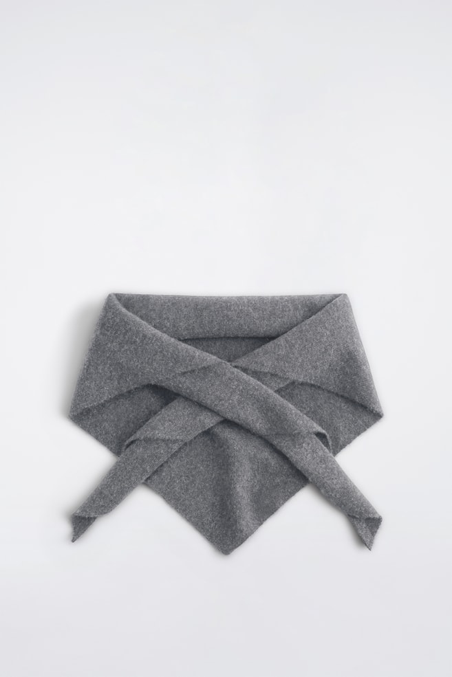 Der Kaschmir-Dreiecksschal liegt flach und zeigt seine mittelgraue Melange-Strickstruktur. Der Schal prÃ¤sentiert ein dreieckiges Design, wobei die Spitze nach unten zeigt und die beiden Enden sich vorne Ã¼berkreuzen. - 1