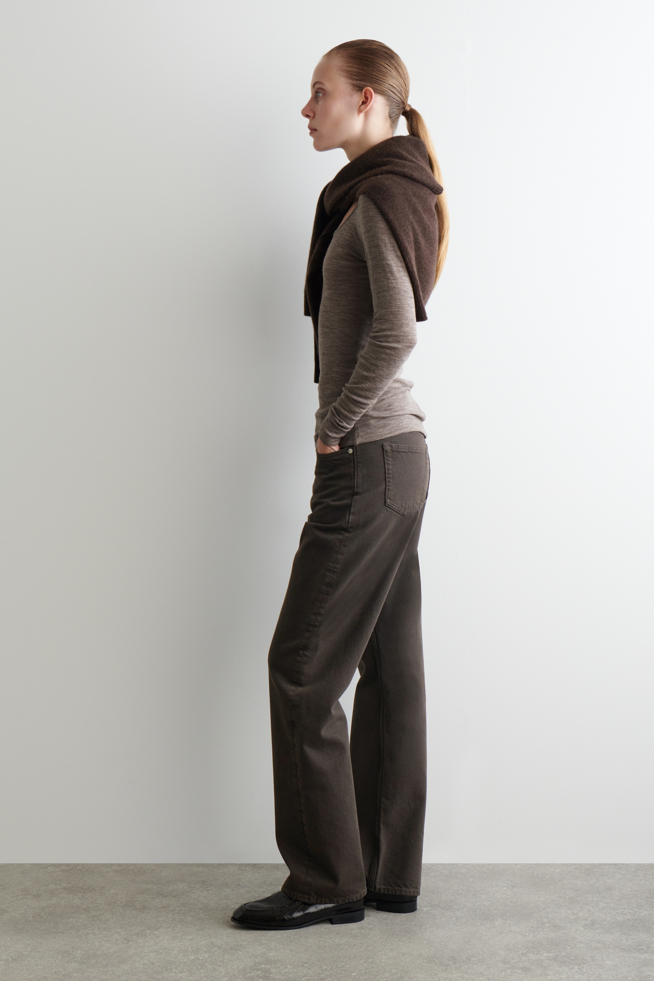 View larger image: A finely knitted, slim-fit, light brown-mélange long-sleeved top, featuring a softly scooped neckline, is being worn underneath a dark brown sweater draped over the shoulders, facing left.