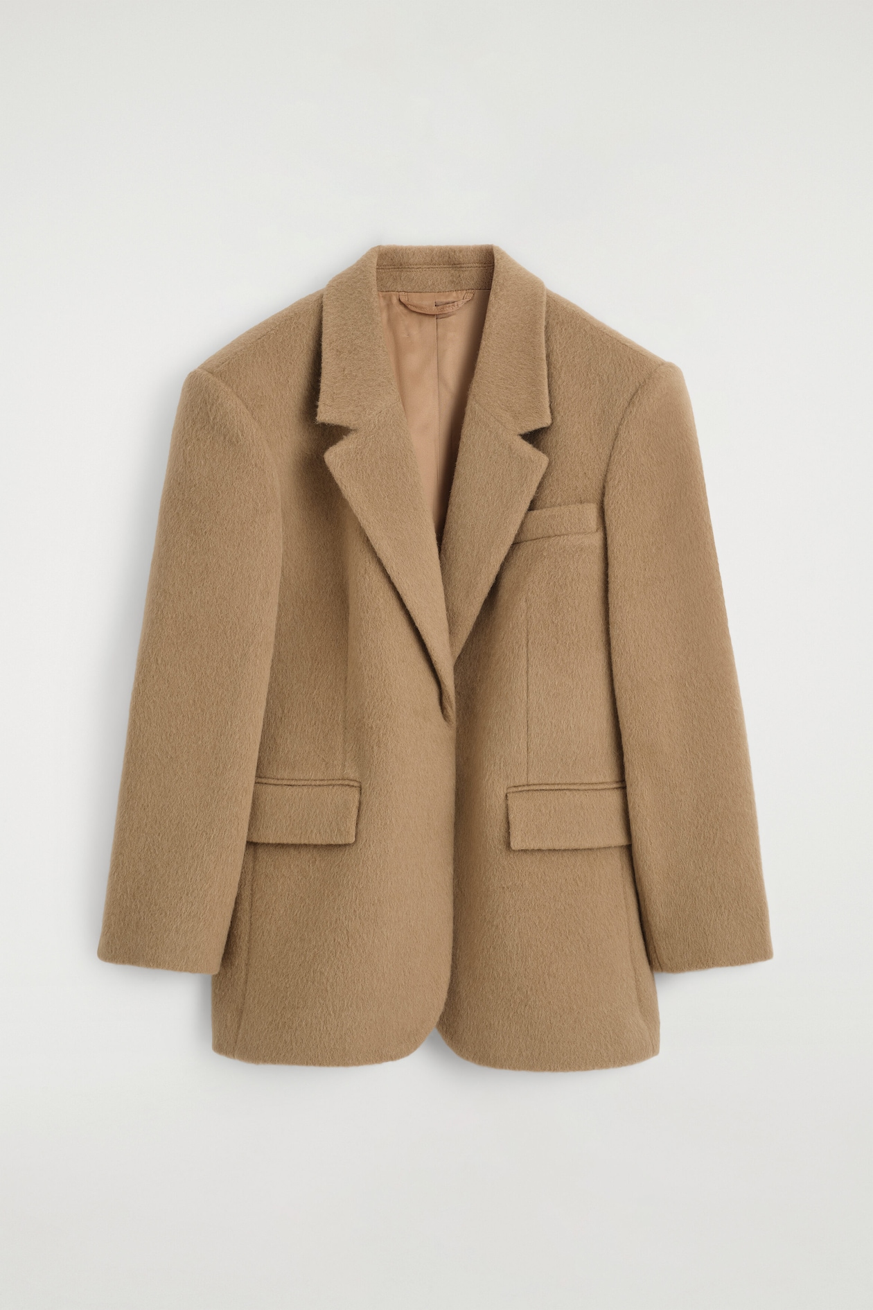 A camel-colored brushed wool blazer is shown from the front, featuring a textured finish, structured shoulders, and prominent notch lapels. The blazer includes two lower flap pockets, a welt chest pocket, and a smooth matching inner lining.