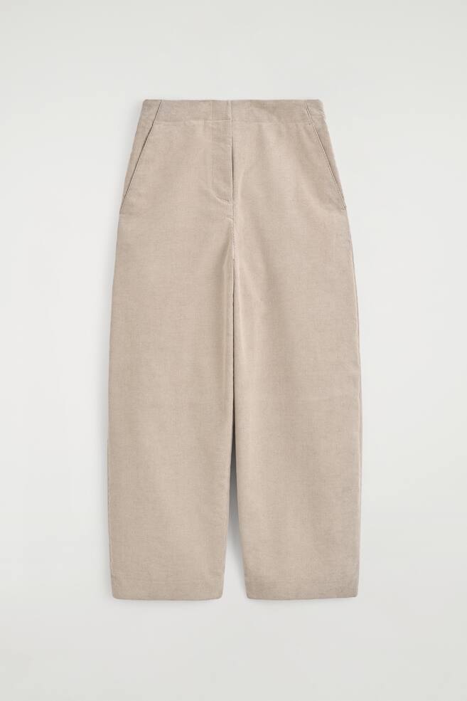 Cord-Hose mit Barrel-Leg-Schnitt in einem hellen Beigeton, von vorn gezeigt, mit hoher Taille, seitlichen Eingrifftaschen und einer weit geschnittenen, geschwungenen Bein-Silhouette, die zum Saum hin leicht zulÃ¤uft. Das KleidungsstÃ¼ck zeigt eine feine Cordstruktur sowie einen klaren, formstabilen Bund mit verdecktem Verschluss. - 1