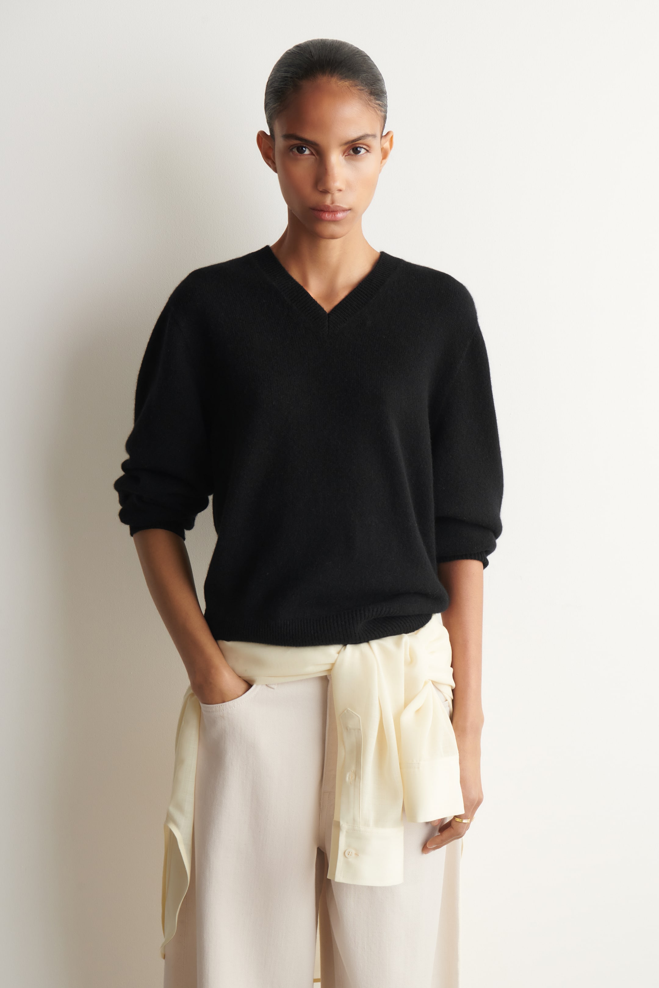 View larger image: A black V-neck jumper is being worn front-facing, featuring a regular fit, sculpted sleeves pushed up, and ribbed trims at the hem and cuffs.