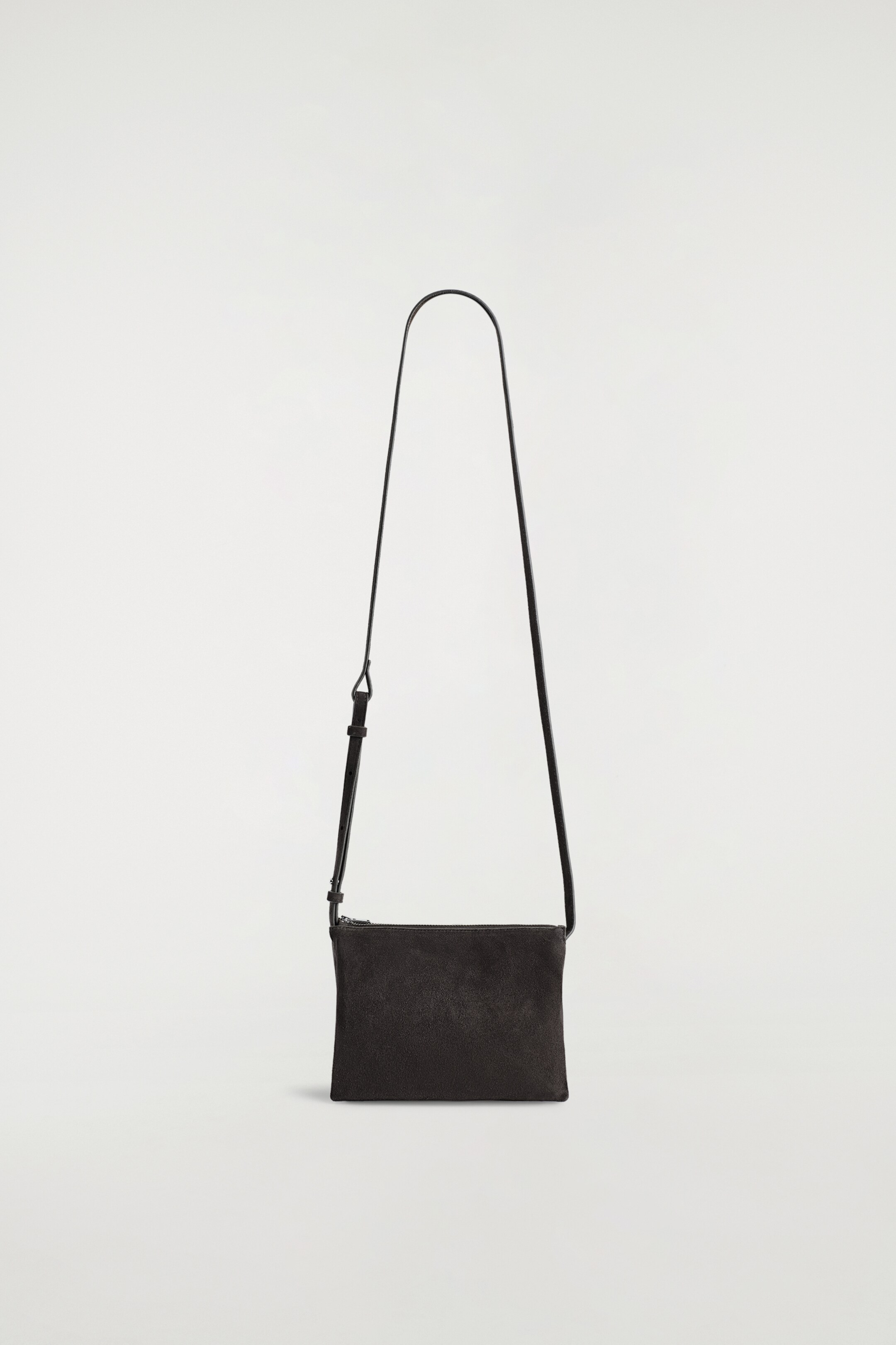 Visualizza immagine più grande: Una borsa a tracolla in camoscio scuro e rettangolare è appesa verticalmente, mostrando la sua parte anteriore. Presenta una sottile tracolla nera regolabile e una chiusura con cerniera superiore.