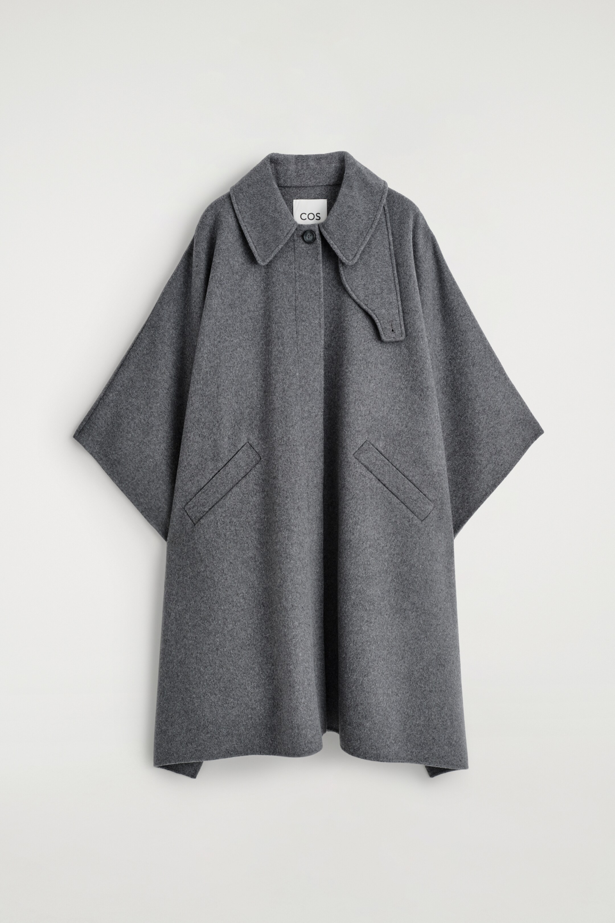 Agrandir l'image: Un long manteau en laine à double face est exposé de face, arborant une couleur gris foncé, un col classique à pointe et une fermeture par bouton unique au niveau du cou. Le manteau présente également deux poches en biais passepoilées et un détail de patte de gorge détachable sur le côté droit du col.