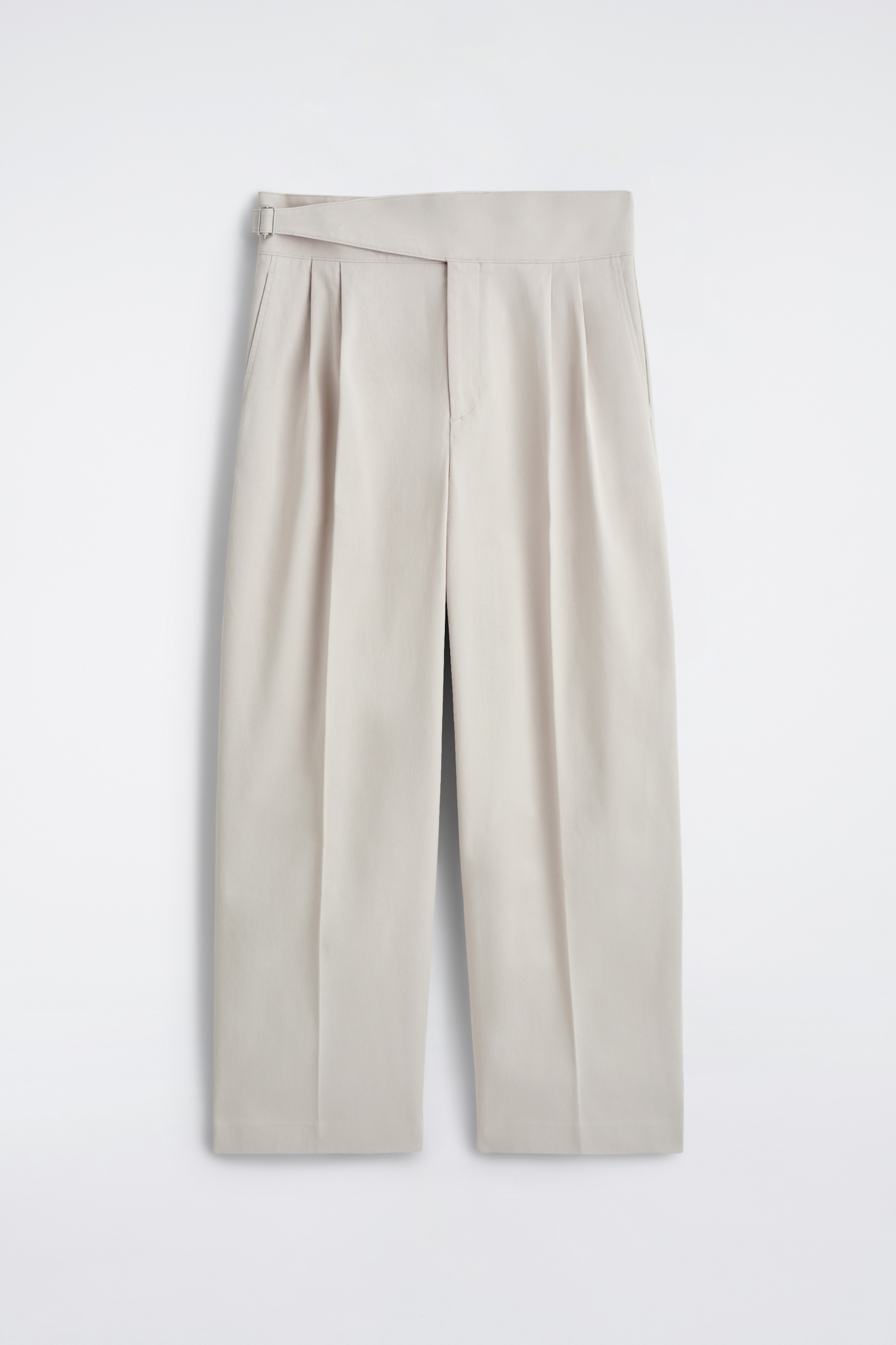 Agrandir l'image: Un pantalon large de couleur beige clair présente une vue de face, doté d'une ceinture style cummerbund avec une ceinture intégrée se fermant avec une boucle rectangulaire sur la gauche. Des plis doubles sont visibles sur le devant de chaque jambe, tombant à partir de la ceinture.