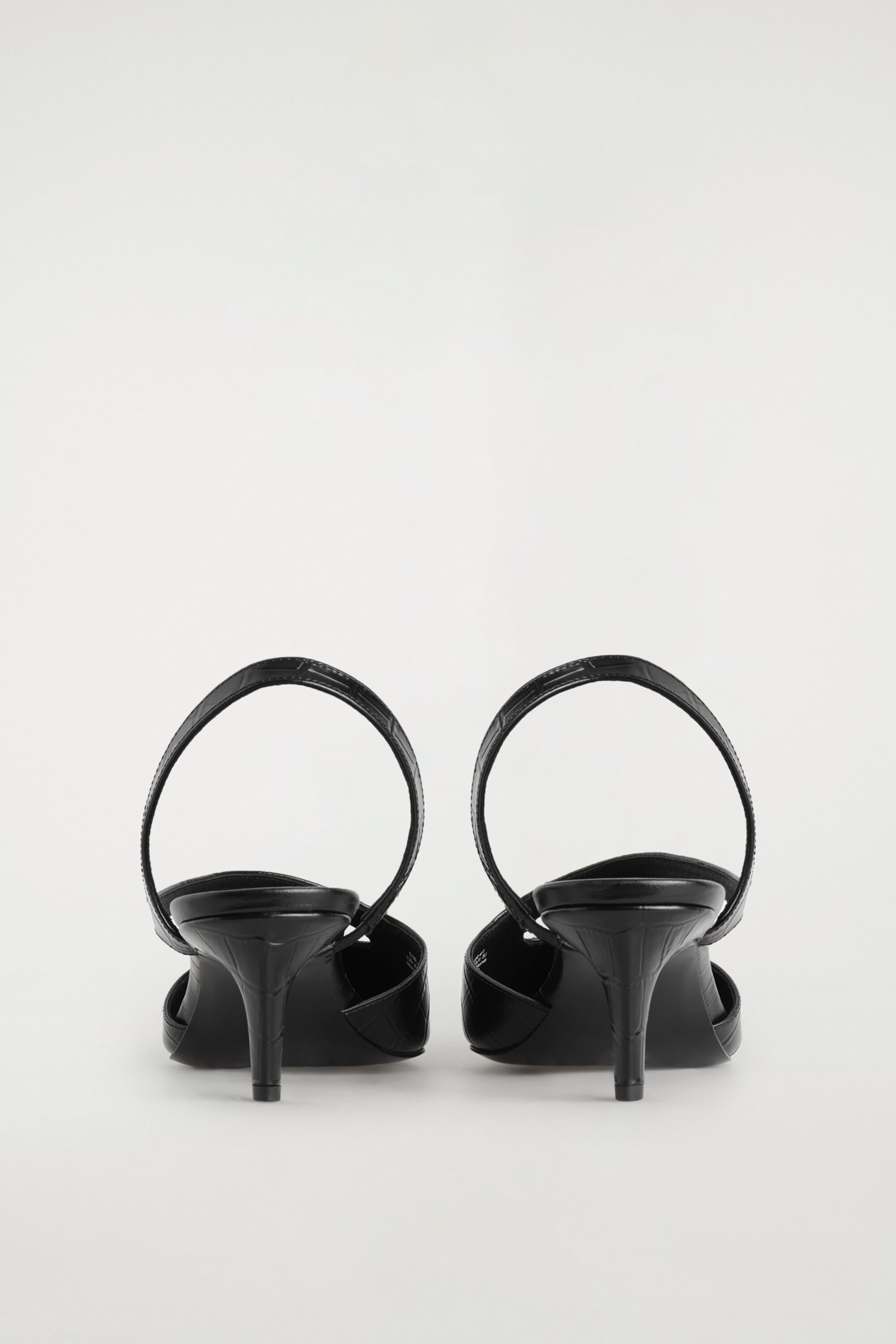 A pair of black croc-effect leather slingback pumps is shown from the back, highlighting their slim heels and rounded slingback straps. The textured, embossed leather covers the heels and straps, emphasizing the structured design. A pair of black croc-effect leather slingback pumps is shown from the back, highlighting their slim heels and rounded slingback straps. The textured, embossed leather covers the heels and straps, emphasizing the structured design.