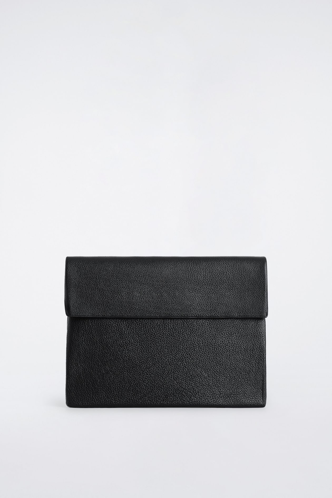 The black leather envelope-style laptop sleeve is shown from the front, highlighting its textured pebbled finish and structured rectangular fold-over flap closure.