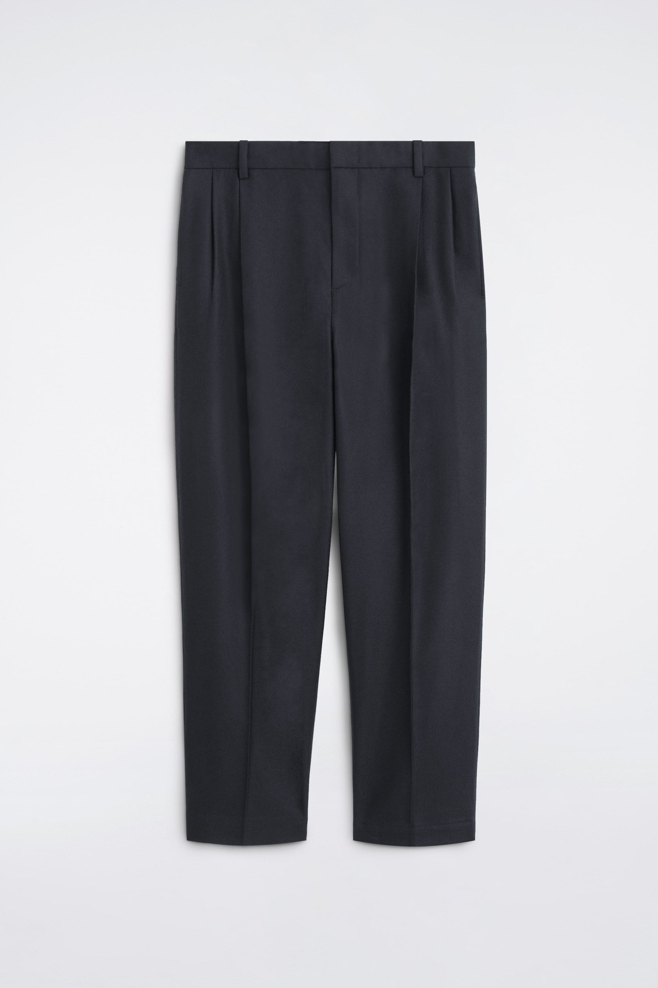 Visualizza immagine più grande: Un paio di pantaloni blu navy scuro è mostrato frontalmente, con vita strutturata con passanti per cintura, pieghe anteriori e pieghe nette che corrono lungo il centro di ciascuna gamba.
