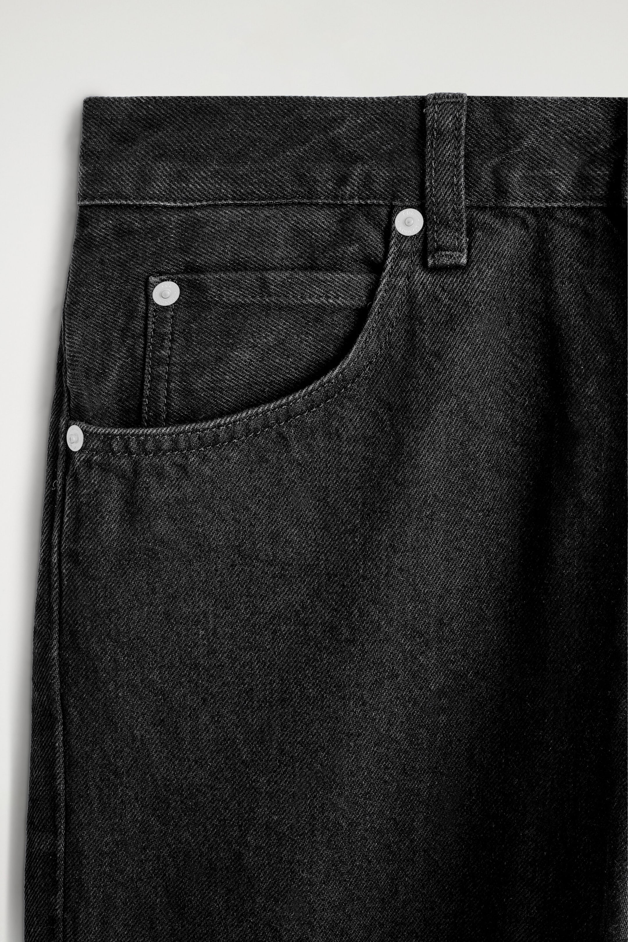 Vue de face en gros plan d’un jean en denim gris foncé, montrant la ceinture, une poche avant incurvée et une petite poche à monnaie. Le modèle présente des rivets métalliques ton argent et une seule passante de ceinture sur la ceinture. Vue de face en gros plan d’un jean en denim gris foncé, montrant la ceinture, une poche avant incurvée et une petite poche à monnaie. Le modèle présente des rivets métalliques ton argent et une seule passante de ceinture sur la ceinture.