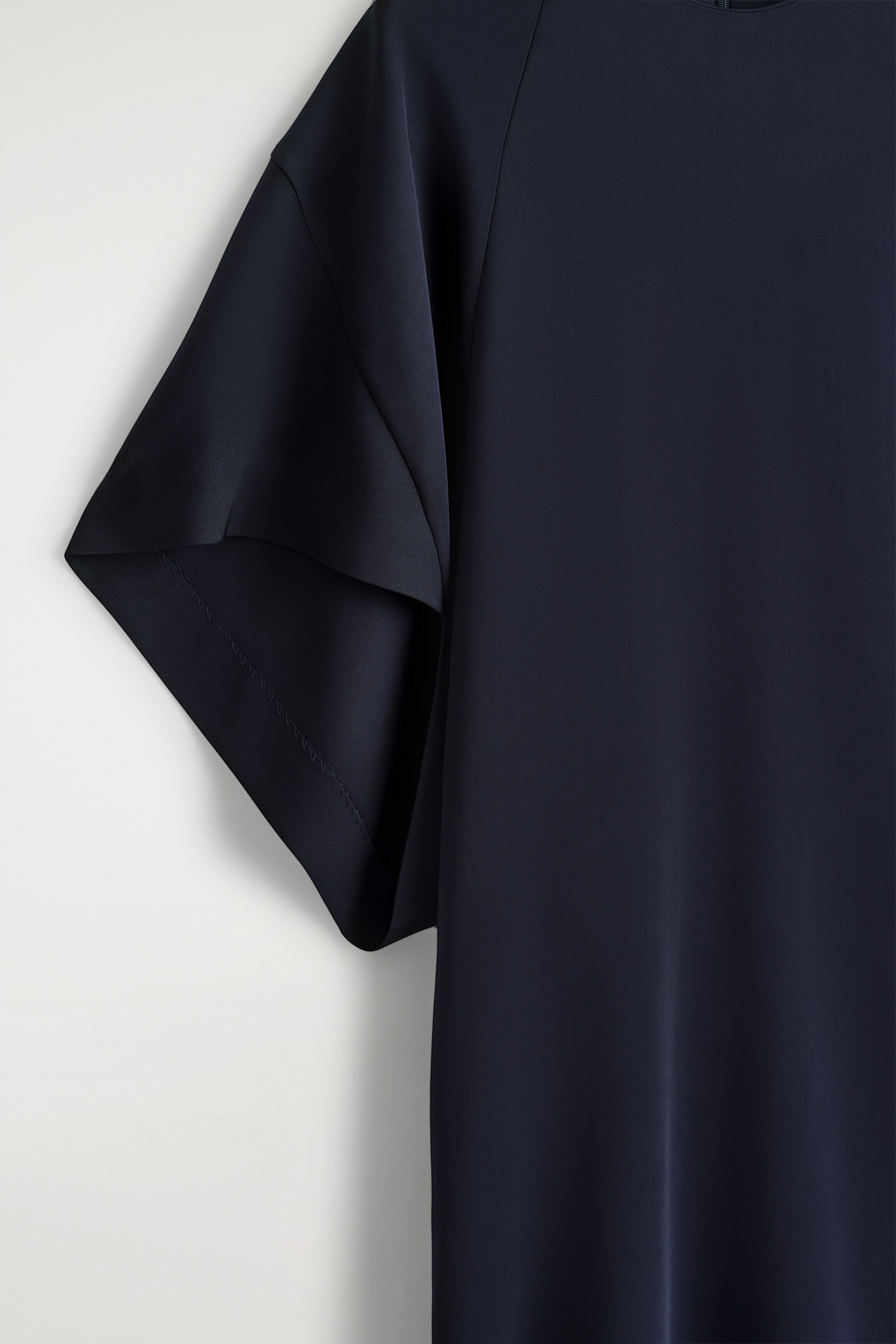 Agrandir l'image: Une robe midi bleu marine de minuit met en valeur son tissu en viscose fluide, qui tombe doucement, et ses manches courtes et larges avec des coutures visibles le long de l'ourlet.