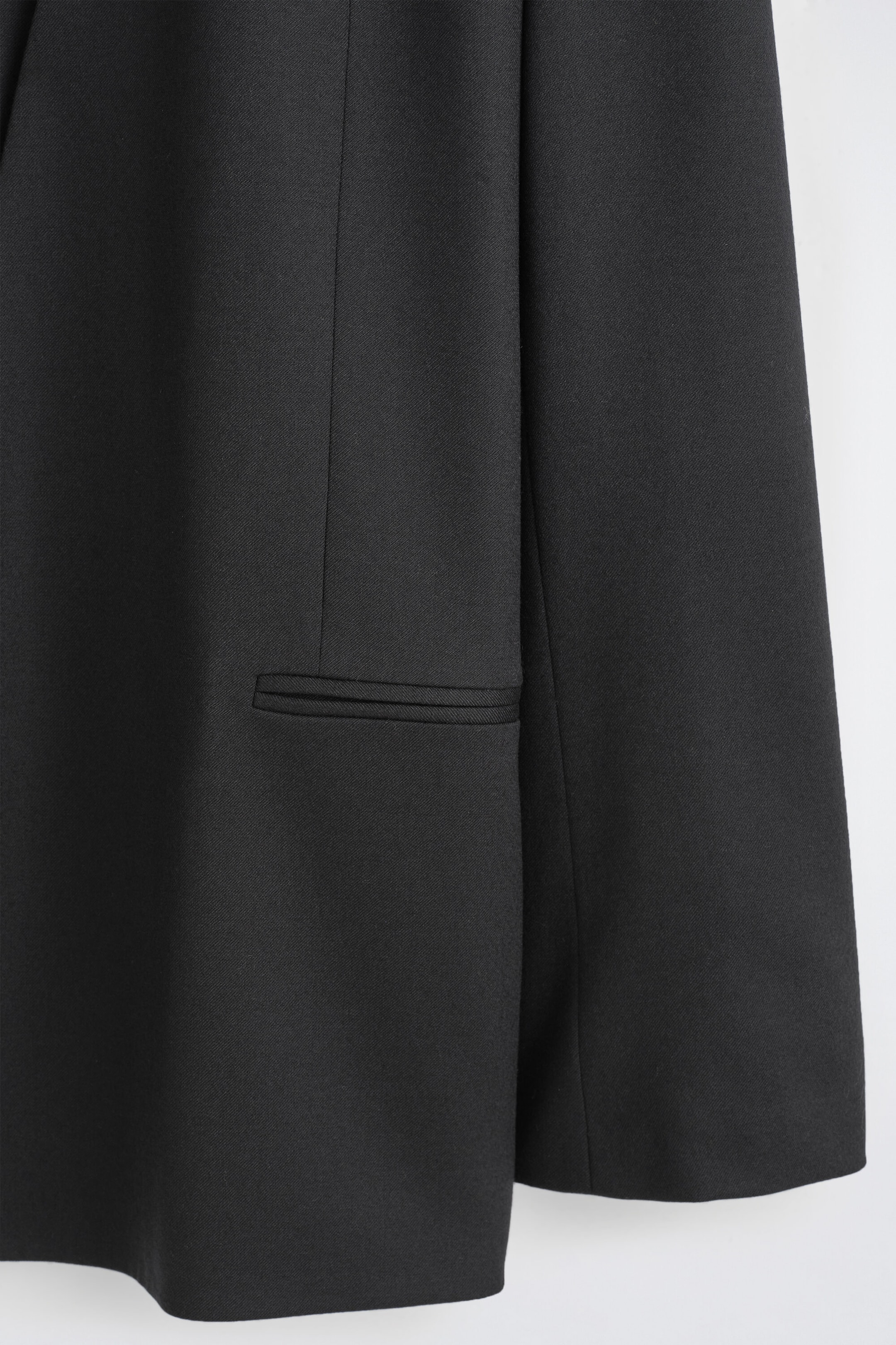 A black blazer features a horizontal welt pocket on the front, made from a finely woven twill fabric. A black blazer features a horizontal welt pocket on the front, made from a finely woven twill fabric.
