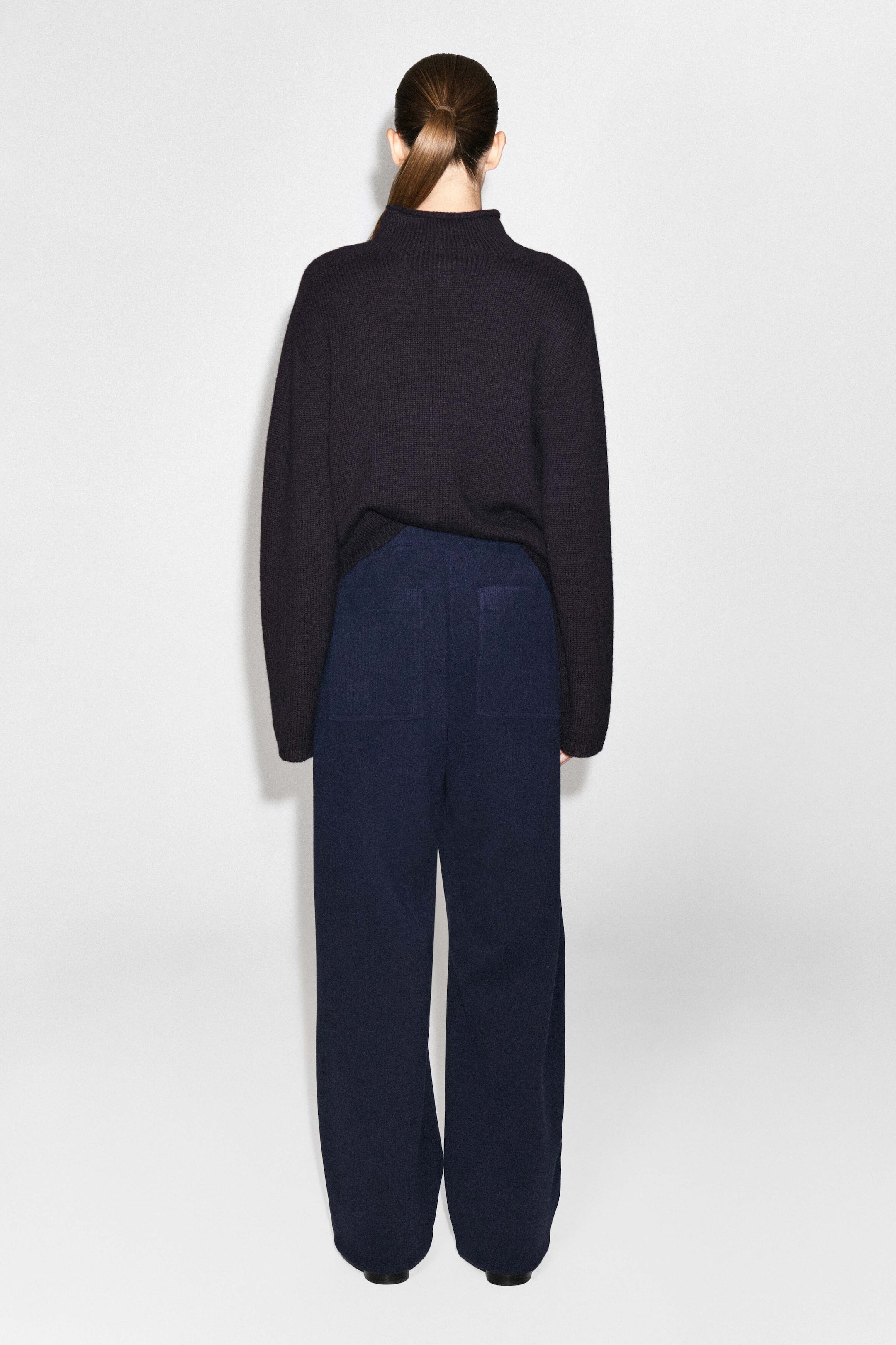 Le pantalon large en jersey côtelé bleu marine foncé est porté par le mannequin, présenté de dos. Le pantalon présente une silhouette décontractée avec deux grandes poches plaquées à l’arrière et est agencé avec un chandail en tricot foncé à col montant. Le pantalon large en jersey côtelé bleu marine foncé est porté par le mannequin, présenté de dos. Le pantalon présente une silhouette décontractée avec deux grandes poches plaquées à l’arrière et est agencé avec un chandail en tricot foncé à col montant.