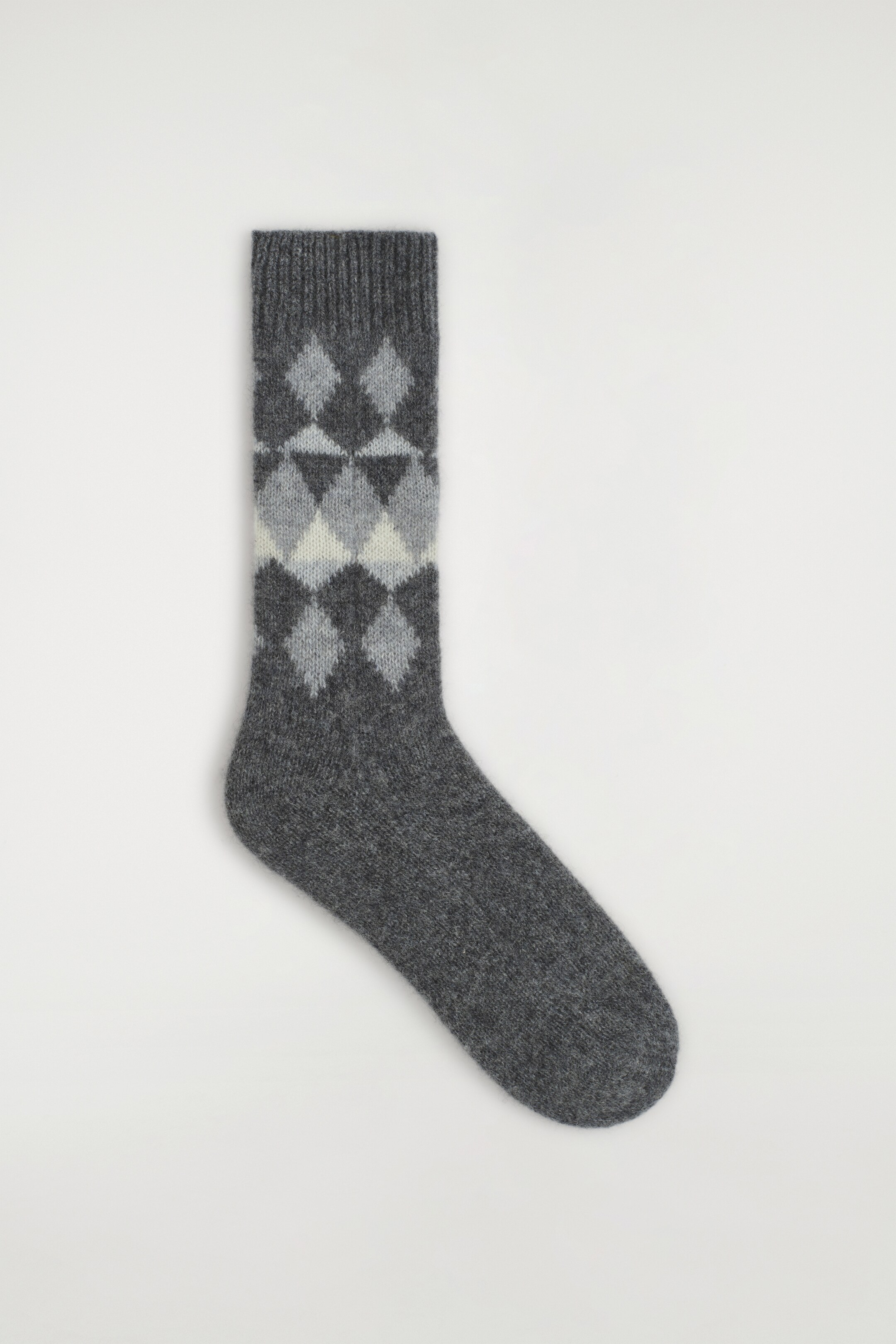 Agrandir l'image: La chaussette gris foncé arbore un motif argyle en diamant en gris plus clair et blanc cassé sur sa jambe et présente une bordure côtelée en haut.