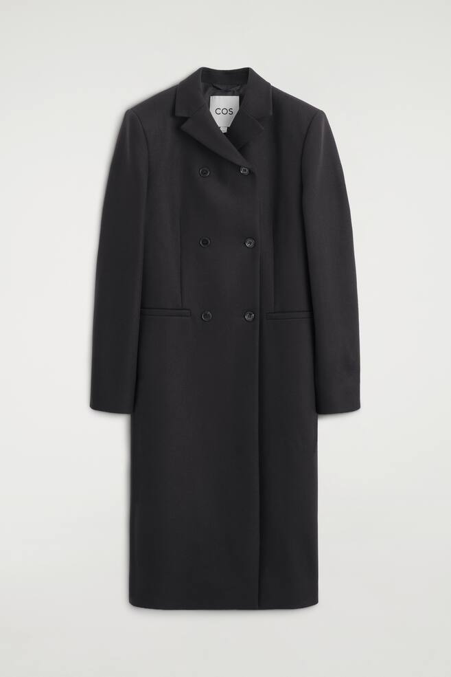 A longline, double-breasted coat in dark grey wool-blend twill is hanging facing the front, featuring structured shoulders, notch lapels and a six-button front fastening. The slim-fit coat also includes two horizontal welt pockets at the waist and long, straight sleeves. - 1