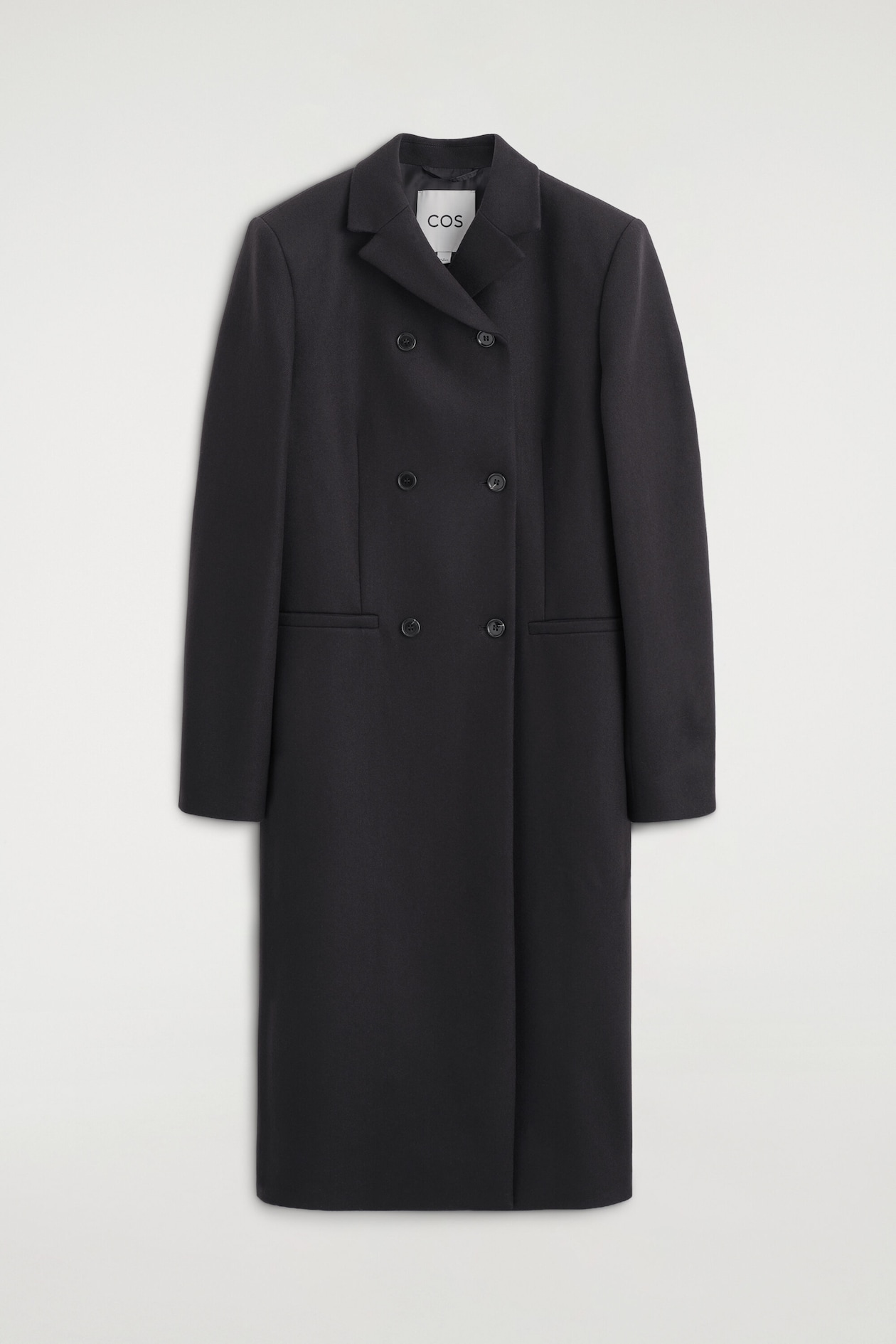 A longline, double-breasted coat in dark gray wool-blend twill hangs facing forward, featuring structured shoulders, notch lapels, and a six-button front closure. The slim-fit coat also includes two horizontal welt pockets at the waist and long, straight sleeves.