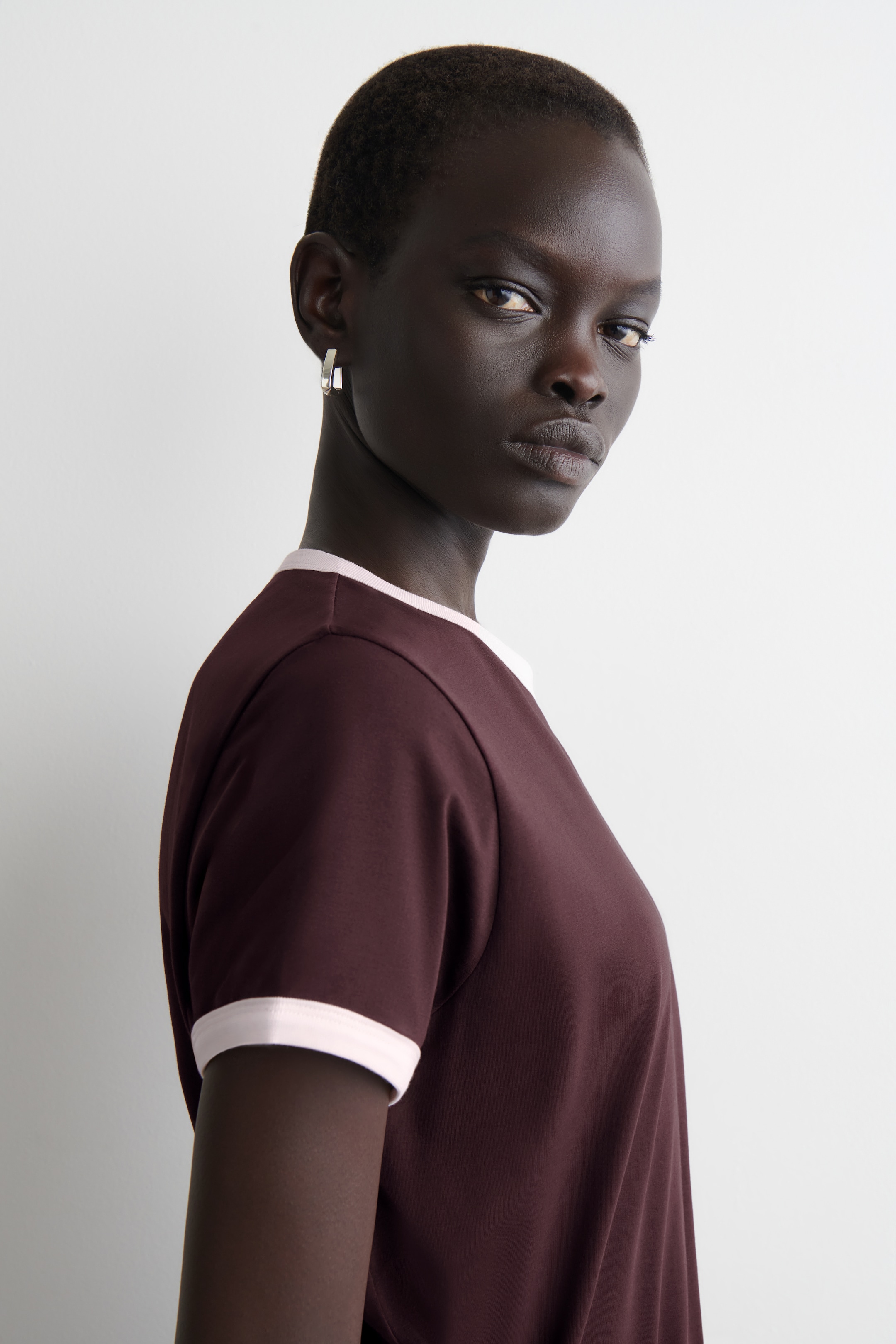 Agrandir l'image: Un t-shirt maroon à col rond est doté d'une bordure rose clair sur son col rond et ses manches courtes.