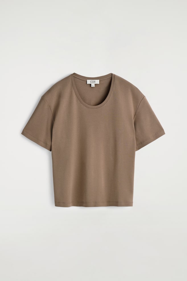 Ein braunes T-Shirt wird VON VORNE präsentiert, mit einem tiefen Ausschnitt und herabfallenden kurzen Ärmeln. Es ist mit einer lockeren Passform und einer glatten Stofftextur gestaltet. - 1
