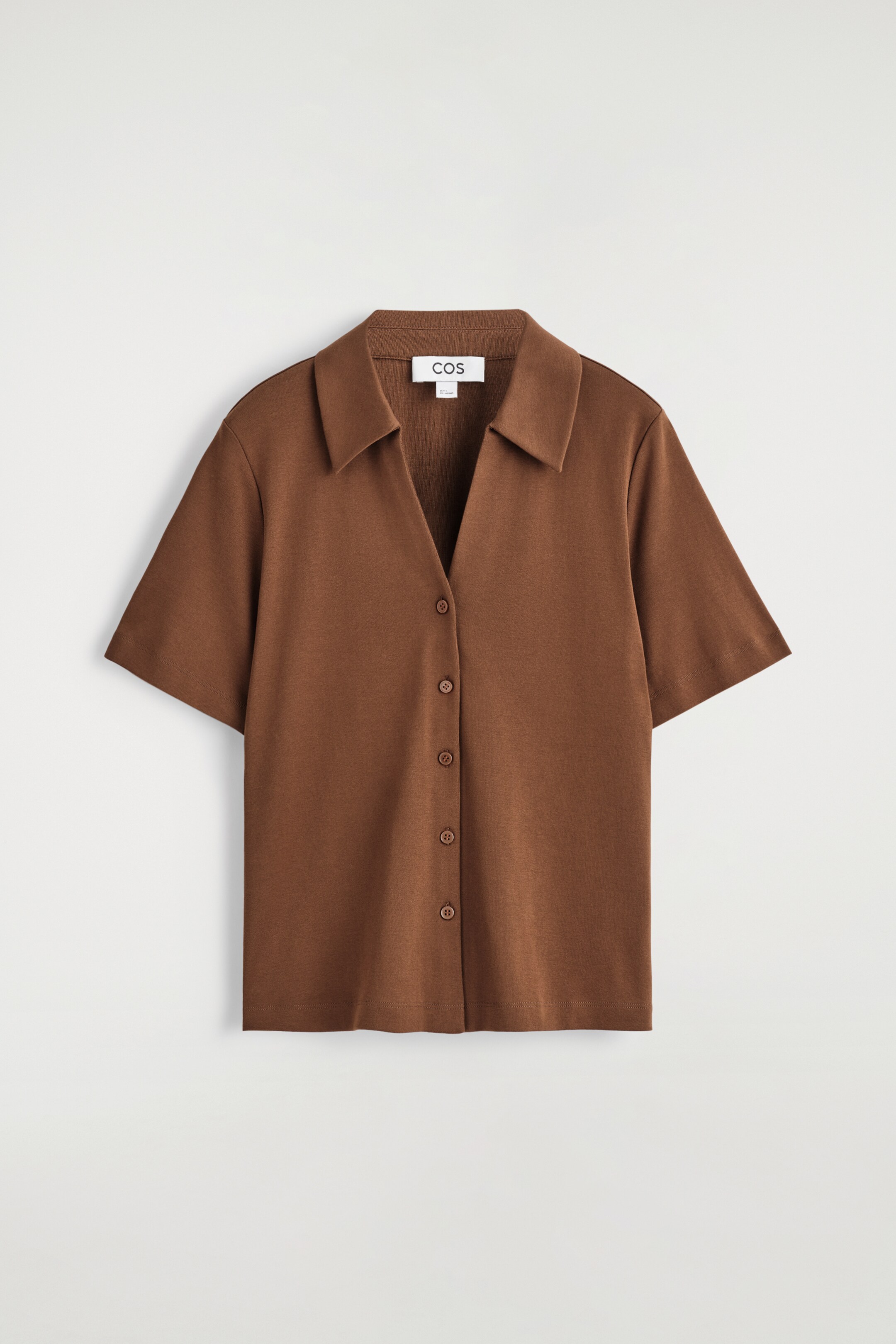 Visualizza immagine più grande: Una camicia da resort marrone a maniche corte è mostrata dal davanti, con un colletto aperto, una chiusura frontale con bottoni tonali e una consistenza morbida simile al jersey.