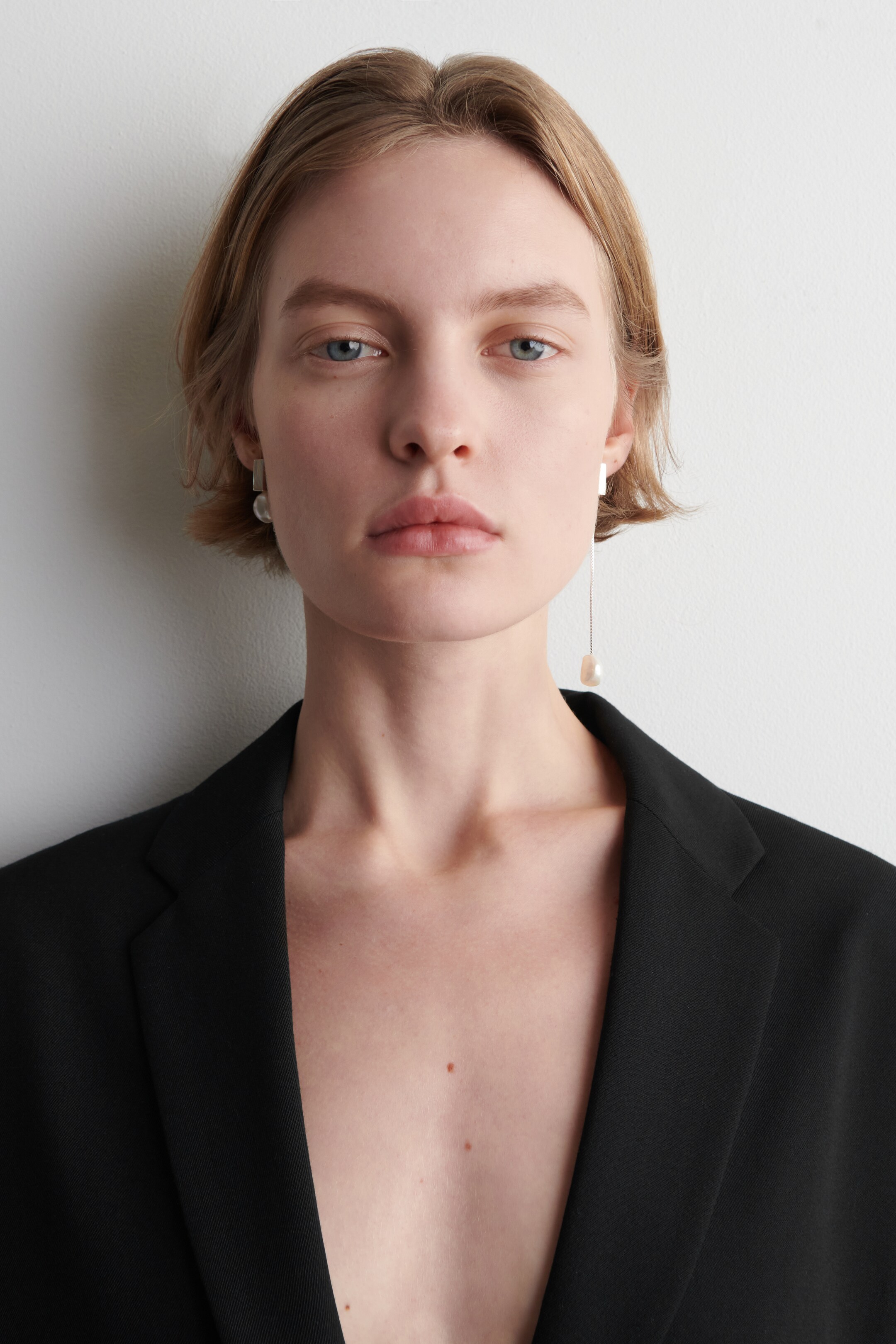 View larger image: A pair of front-facing, mismatched earrings is on display. The left earring features a rectangular silver-toned stud with a round, irregular pearl dangling. The right earring showcases a rectangular silver-toned top with a long chain suspending an elongated, irregular pearl.