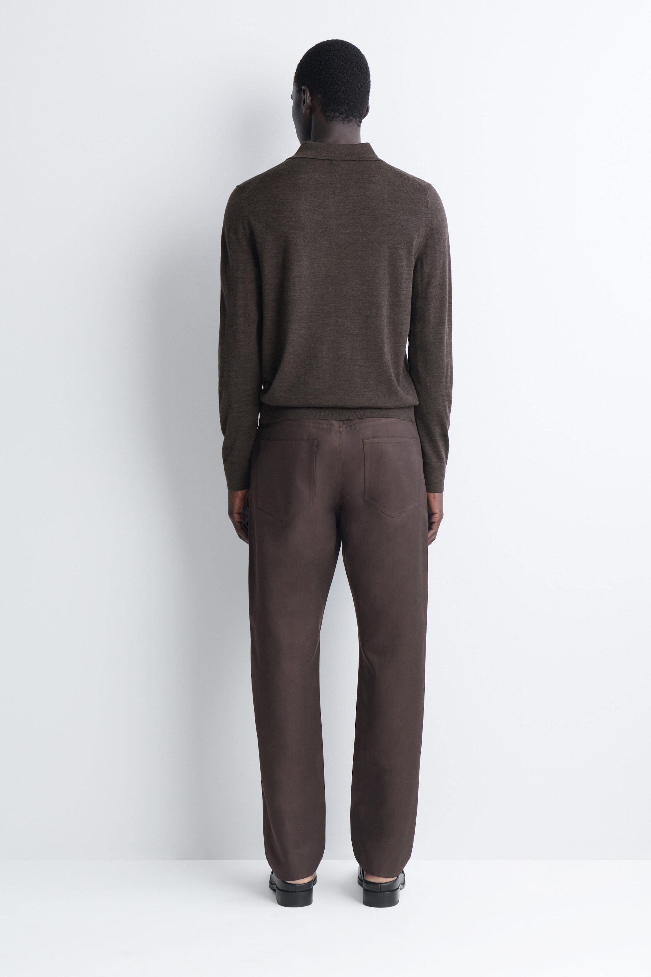 The Signature Regular-Fit Straight-Leg Jeans are shown from the back, featuring dark brown fabric, a straight-leg silhouette, and two rear patch pockets. The jeans are cut in a relaxed, regular fit and are paired with a matching brown knit polo. The Signature Regular-Fit Straight-Leg Jeans are shown from the back, featuring dark brown fabric, a straight-leg silhouette, and two rear patch pockets. The jeans are cut in a relaxed, regular fit and are paired with a matching brown knit polo.